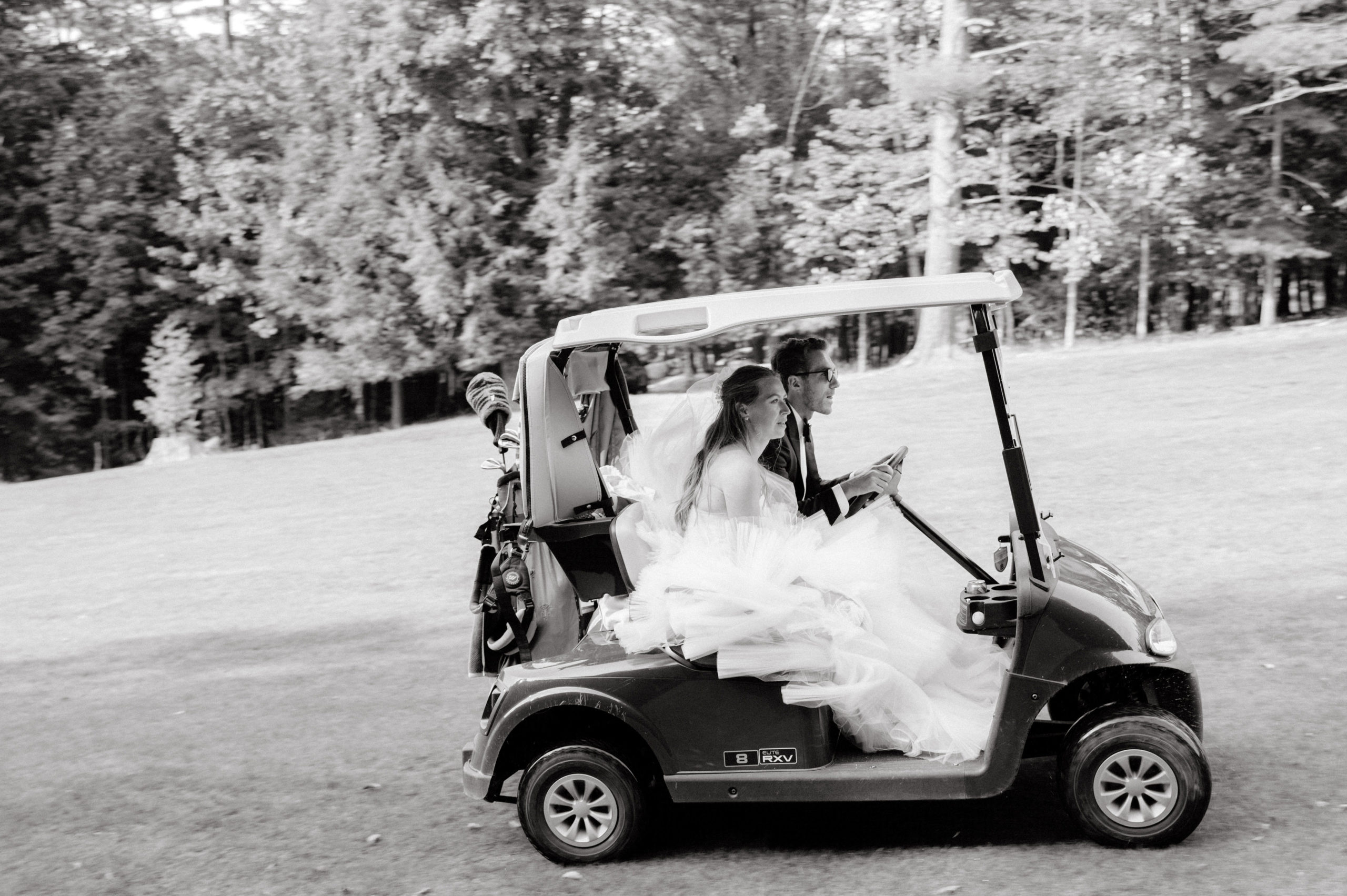 The bride and the groom are riding a golf cart at The Ausable Club, New York. Image by Jenny Fu Studio