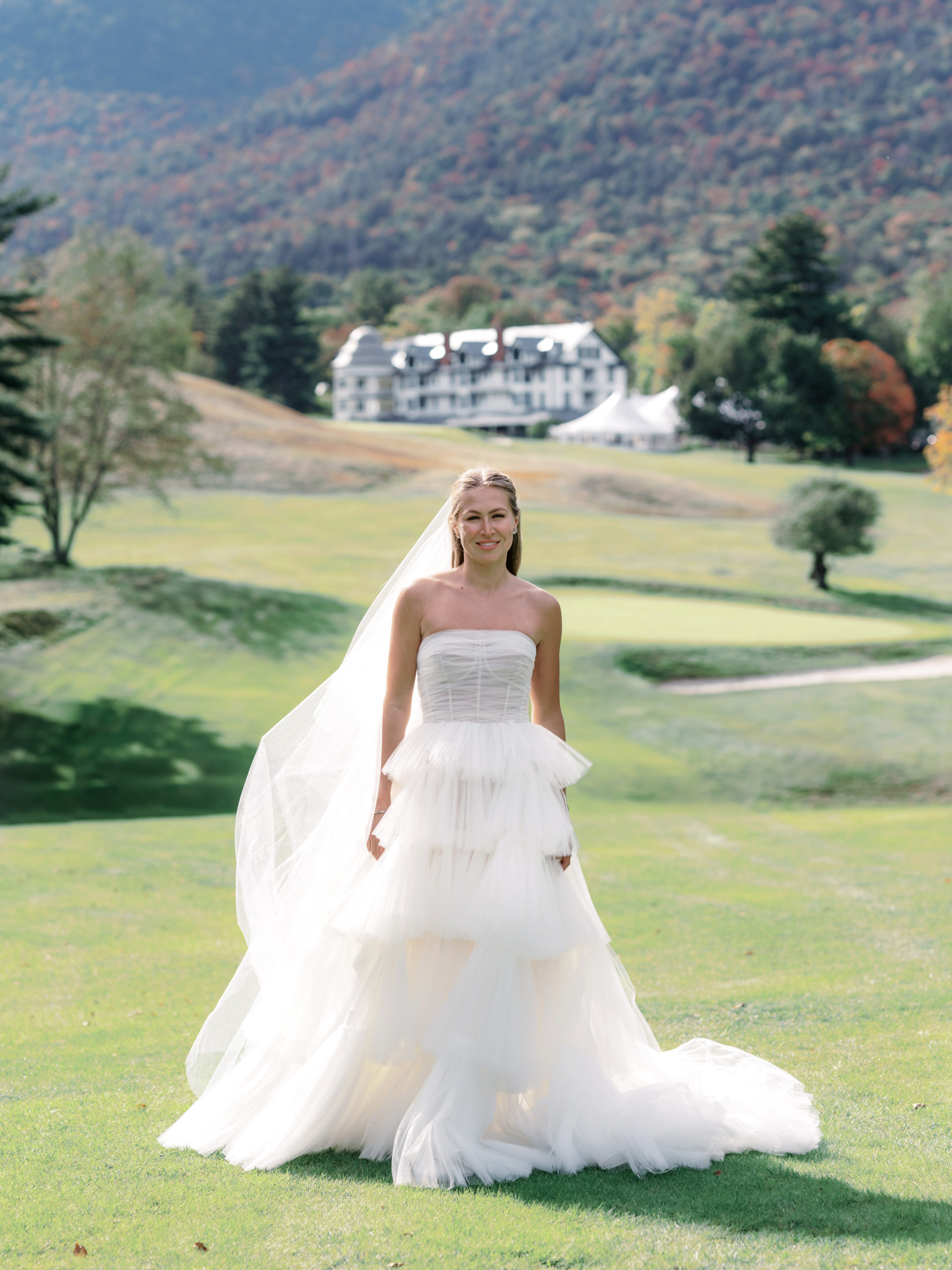 The gorgeous bride is standing in the middle of The Ausable Club's golf course. Image by Jenny Fu Studio