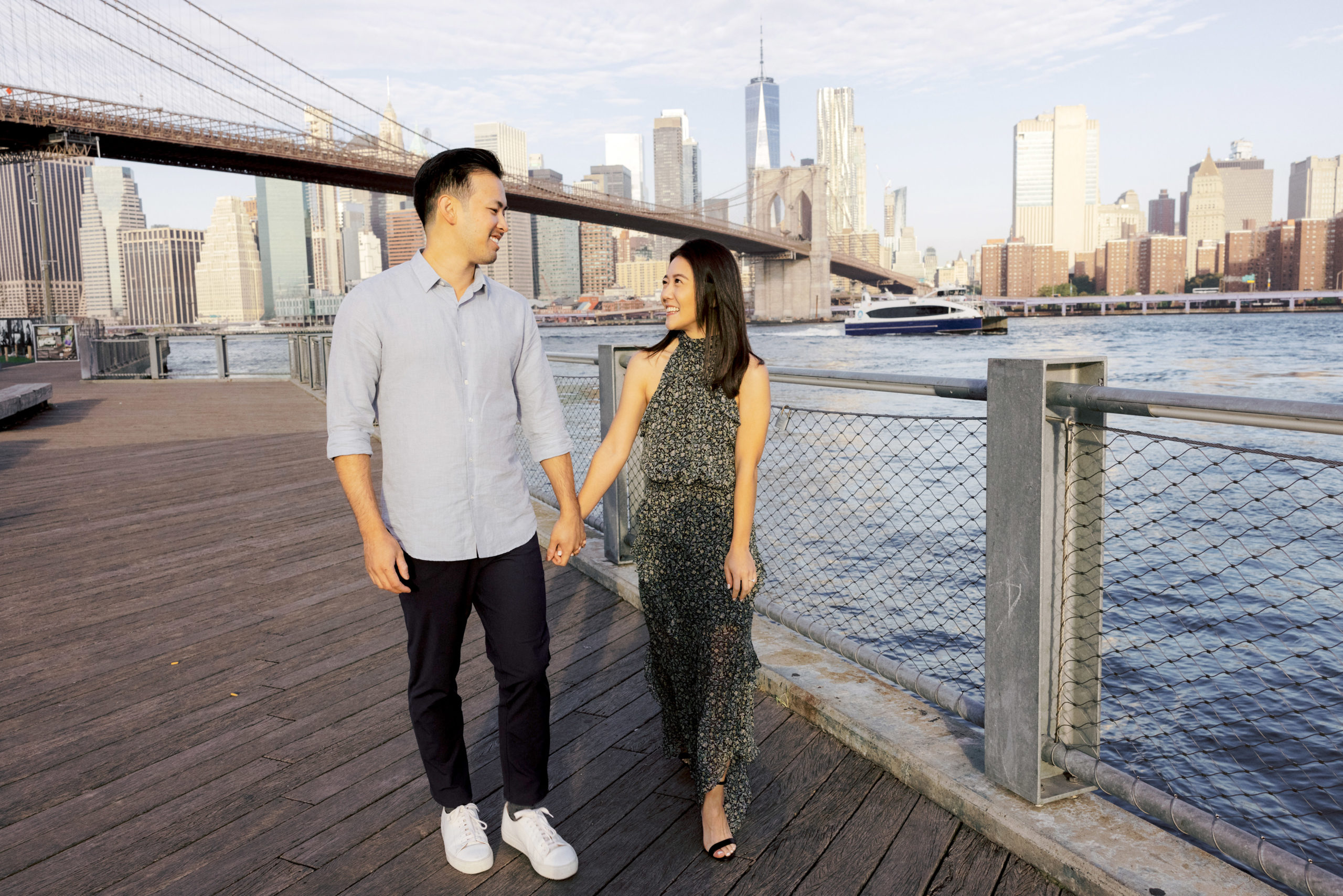 The engaged couple are walking happily with the Brooklyn Bridge in the background. Image by Jenny Fu Studio