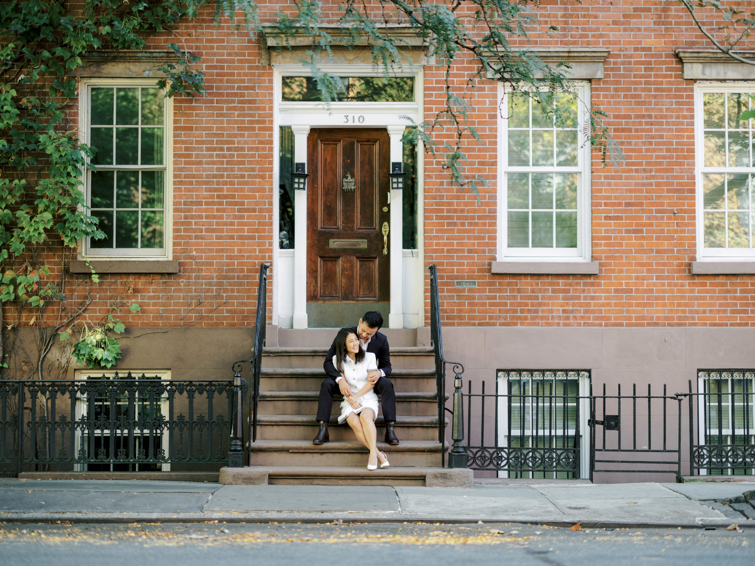 The engaged couple are sitting on the staircase of a house at West Village, NYC. Editorial engagement image by Jenny Fu Studio