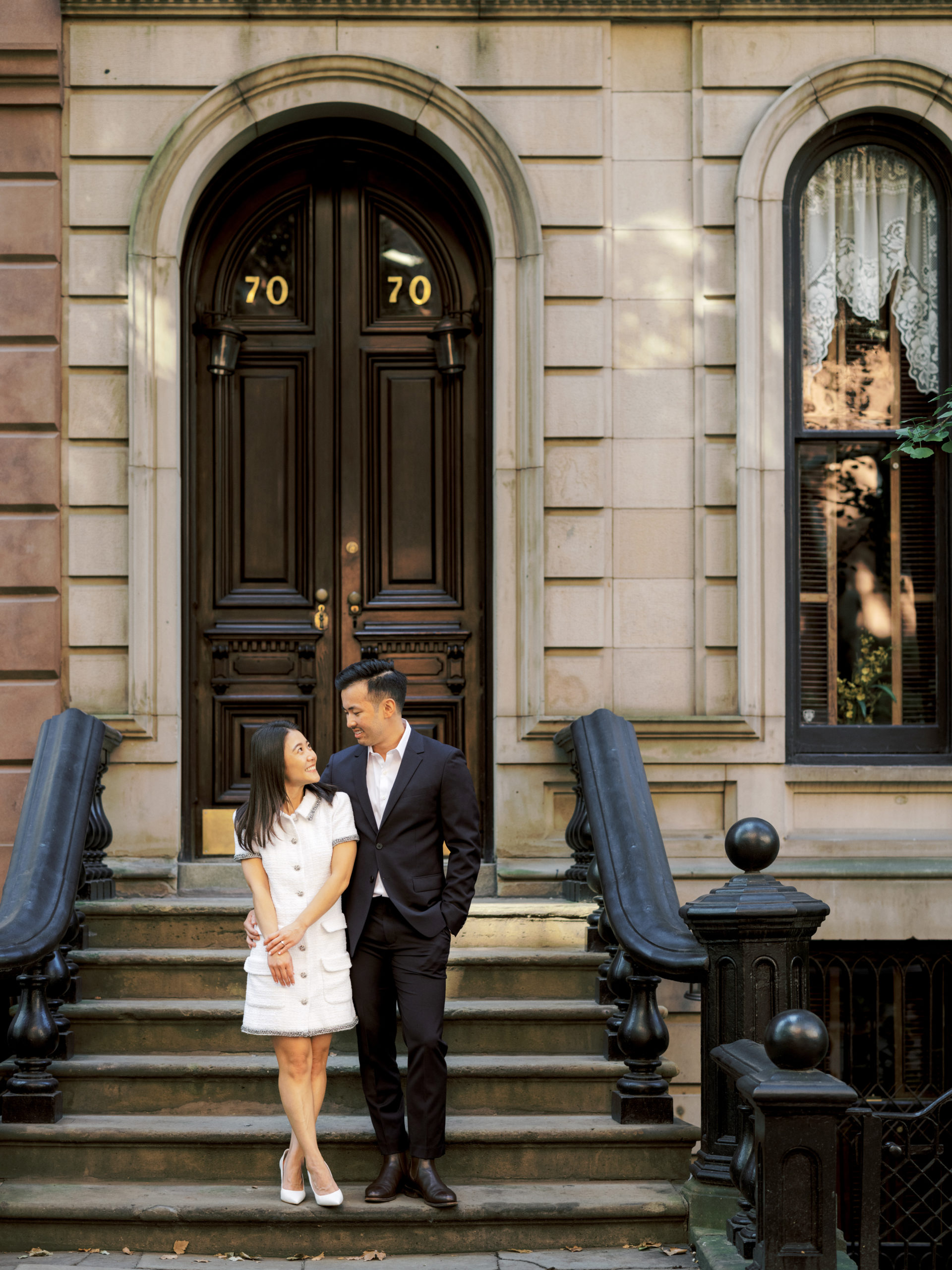 The engaged couple are standing on the staircase of a house in West Village, NYC. Editorial engagement image by Jenny Fu Studio