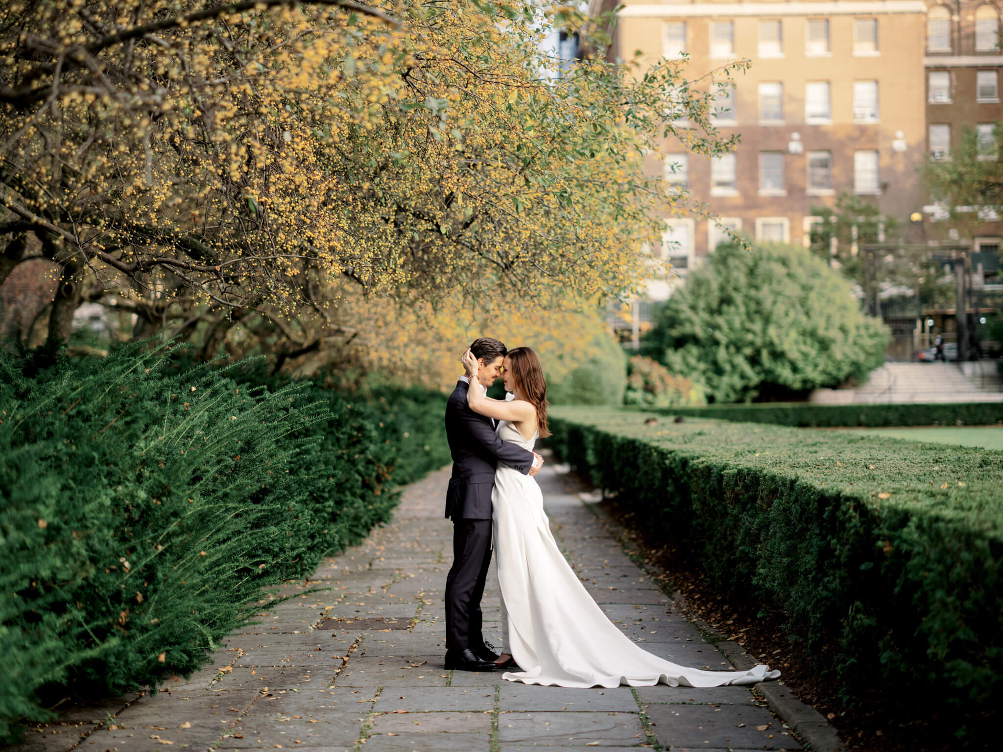 The bride and groom are standing close, head to head, at the Conservatory Garden, NYC. Image by Jenny Fu Studio