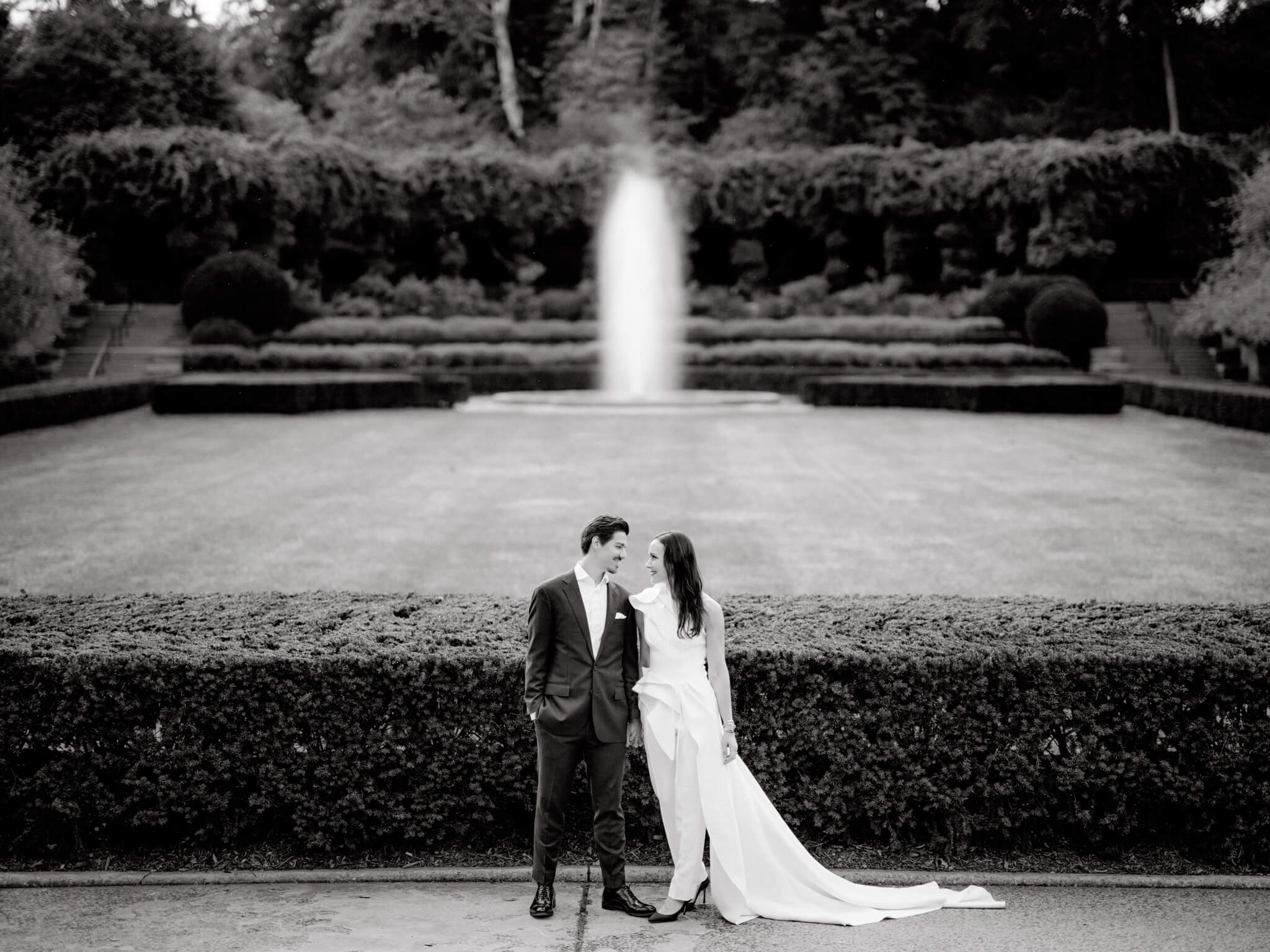 The bride and groom are staring at each other's eyes, with the glorious fountain at the Conservatory Garden in the background. Image by Jenny Fu Studio