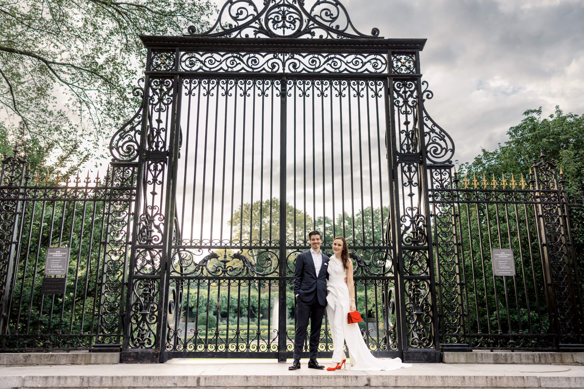 The bride and groom are standing in front of the very large gate of the Conservatory Garden. Image by Jenny Fu Studio