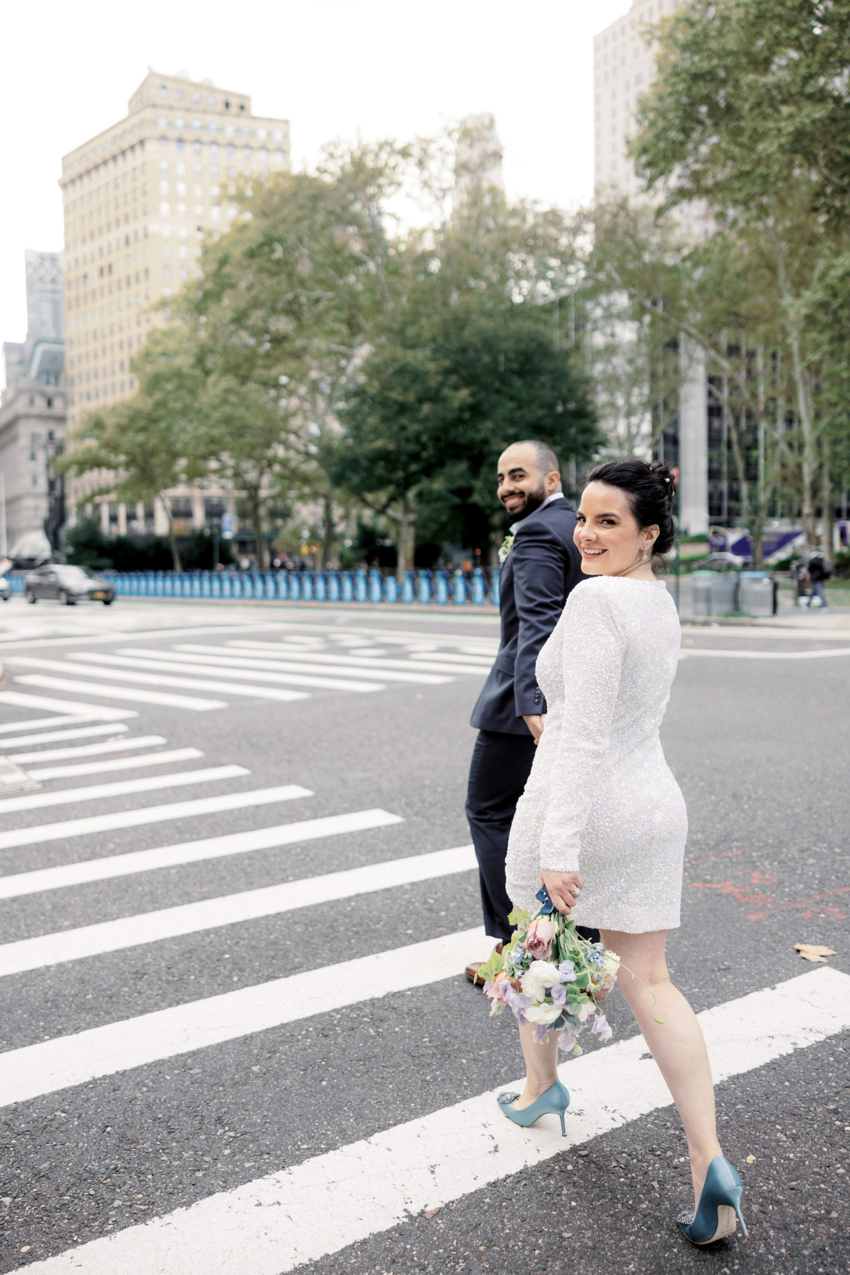 The bride and groom are happily crossing the street after their city hall elopement. 