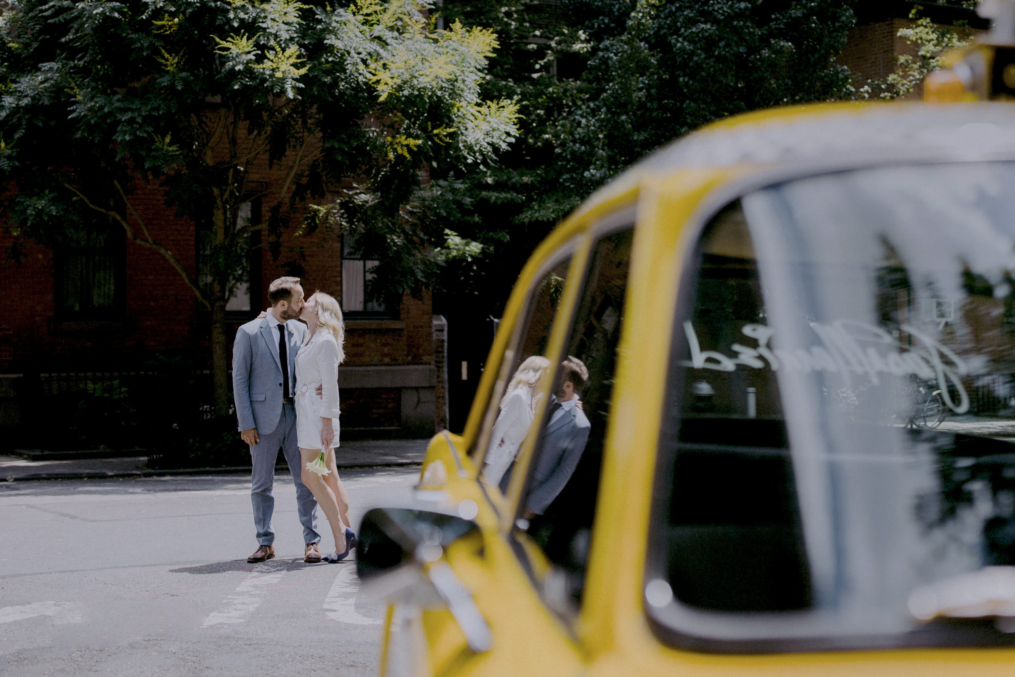 The bride and groom are kissing behind an NYC yellow taxi cab. Elopement image by Jenny Fu Studio
