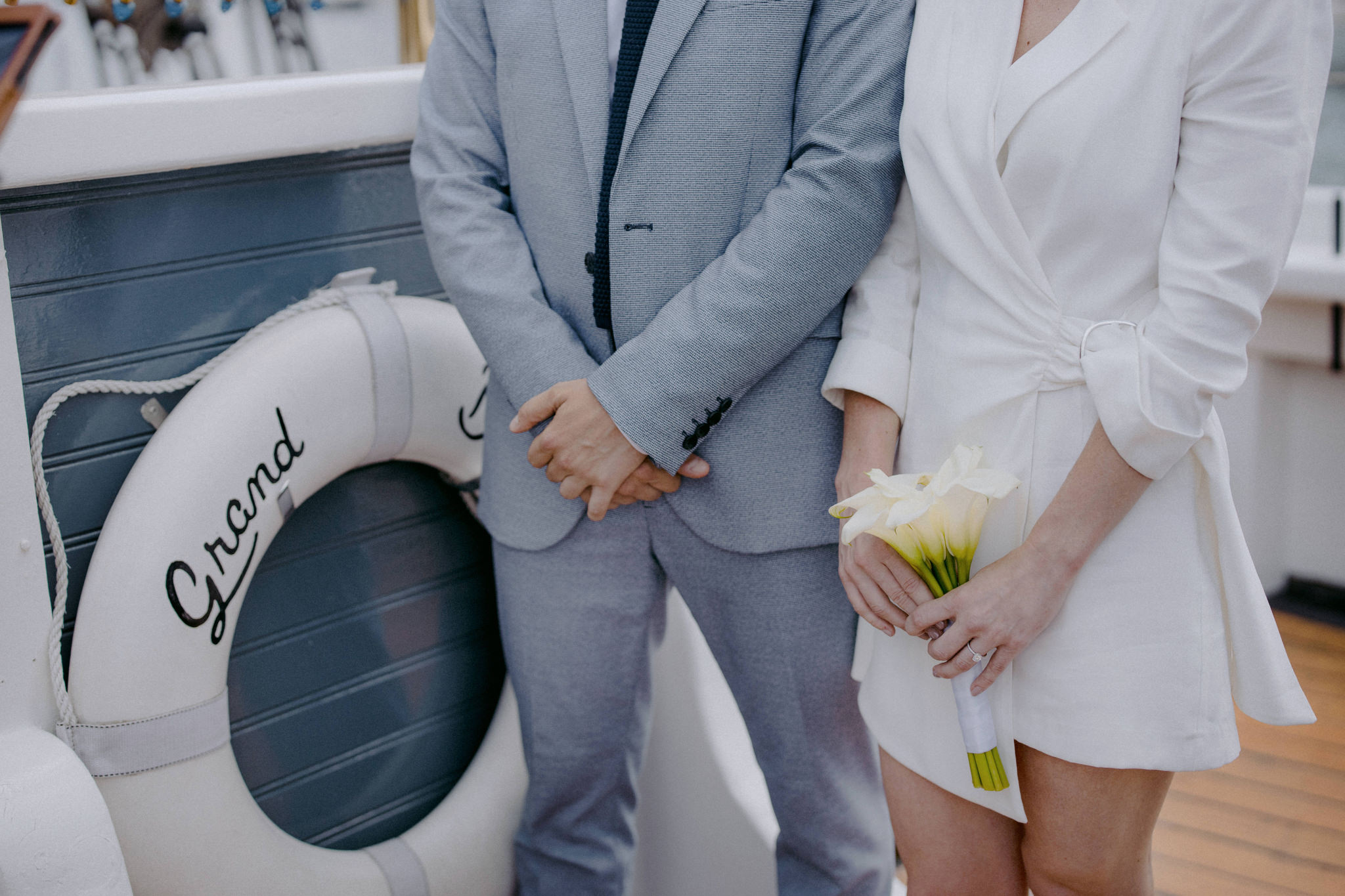 The bride is holding a white flower bouquet while standing with the groom in the wedding ceremony on a boat at NYC. Elopement image by Jenny Fu Studio