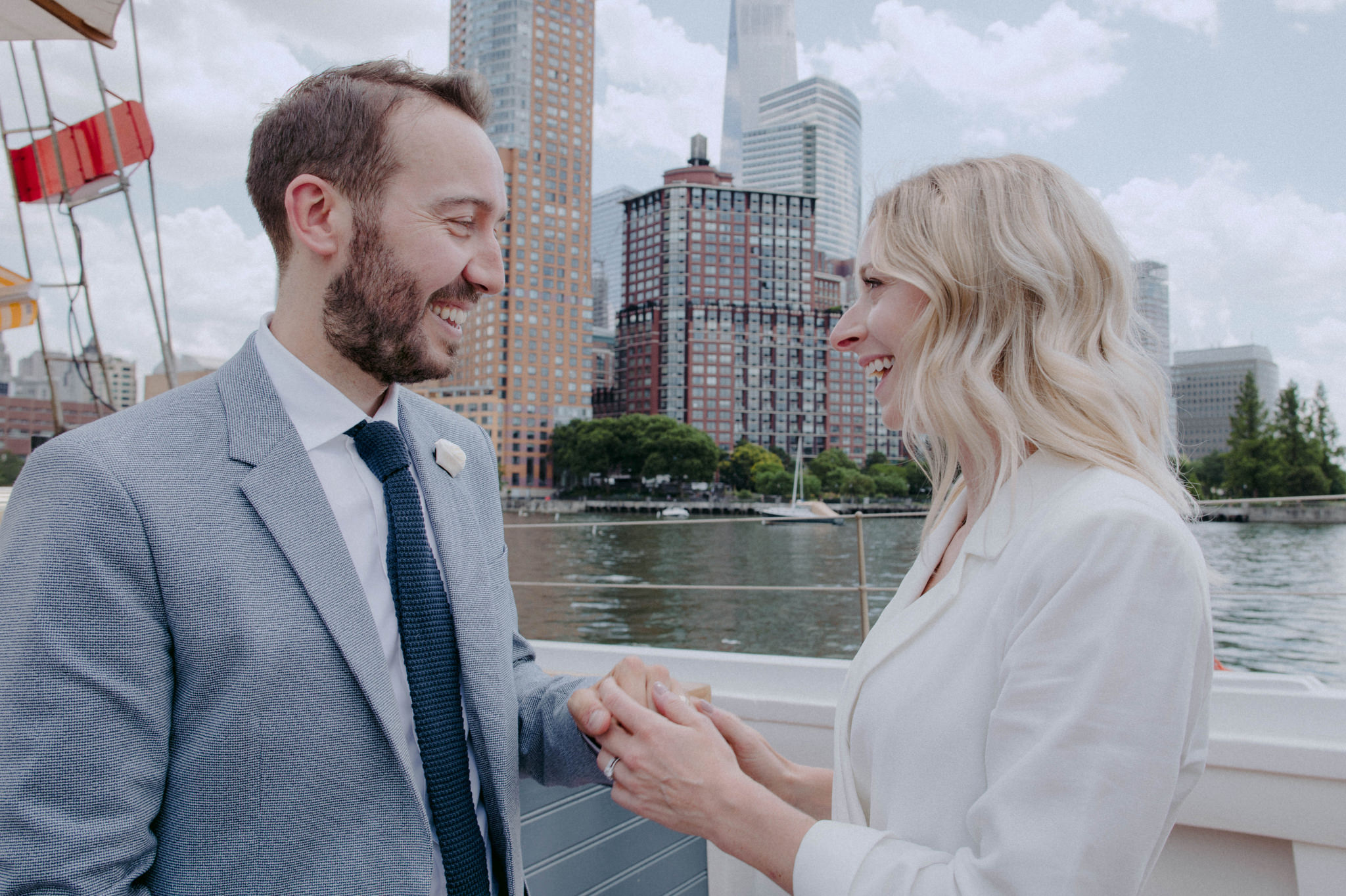 The Bride is holding the groom's hand while smiling at each other in a boat at New York. Intimate wedding image by Jenny Fu Studio
