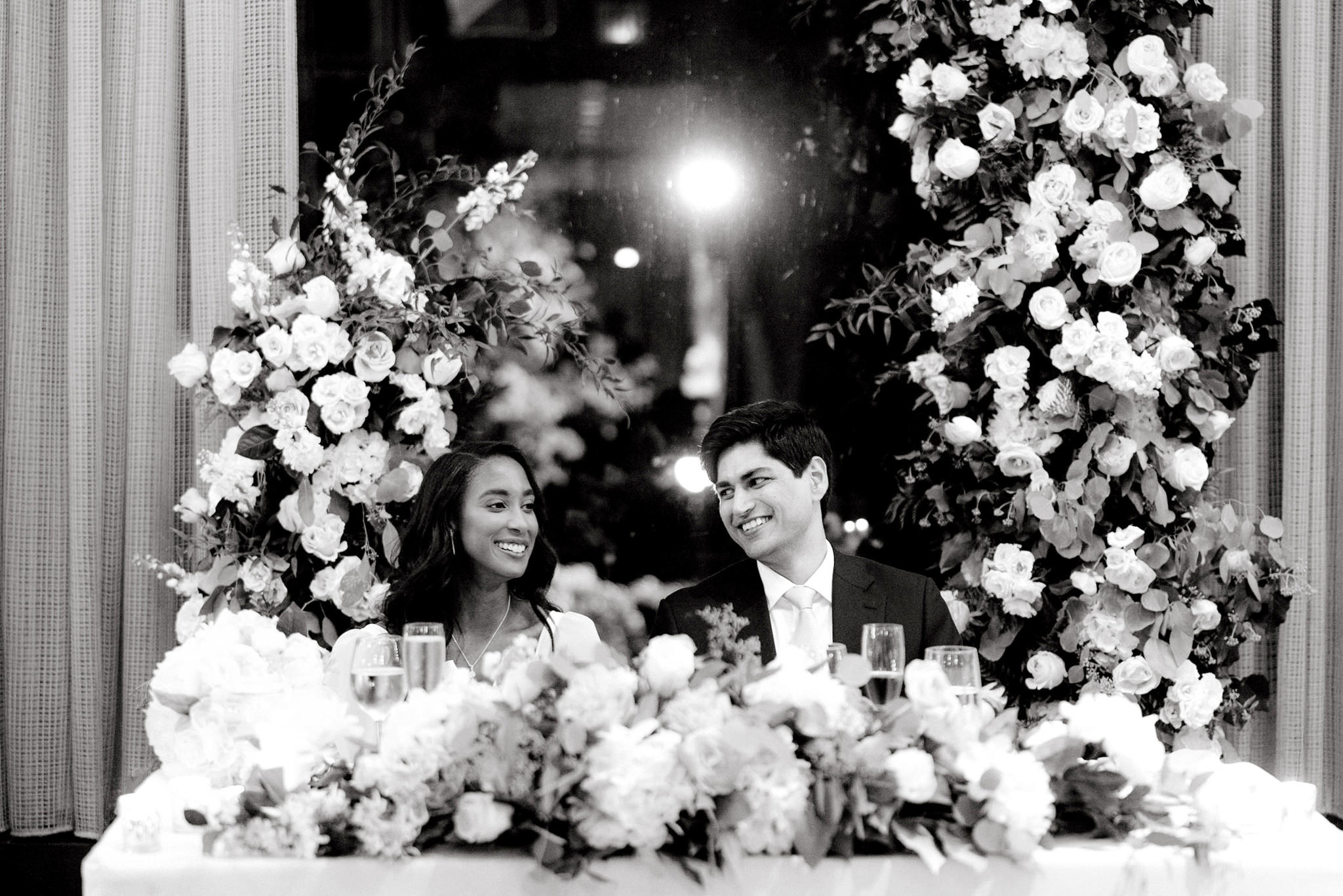 The bride and groom are both smiling while they are seated in their wedding reception. Editorial wedding image by Jenny Fu Studio