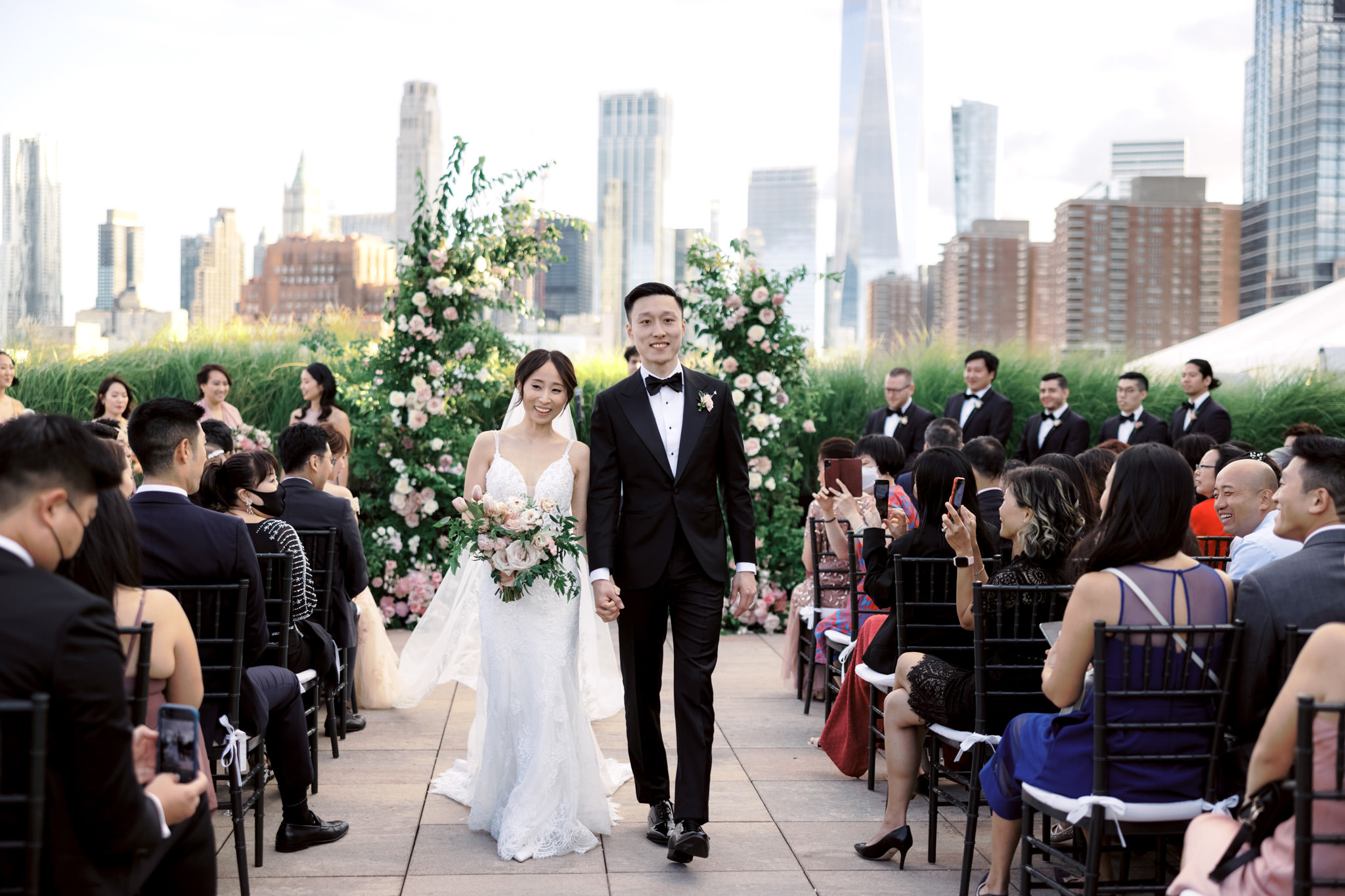 The bride and groom are walking away after the wedding ceremony at a beautiful garden NYC wedding venue. Editorial wedding image by Jenny Fu Studio