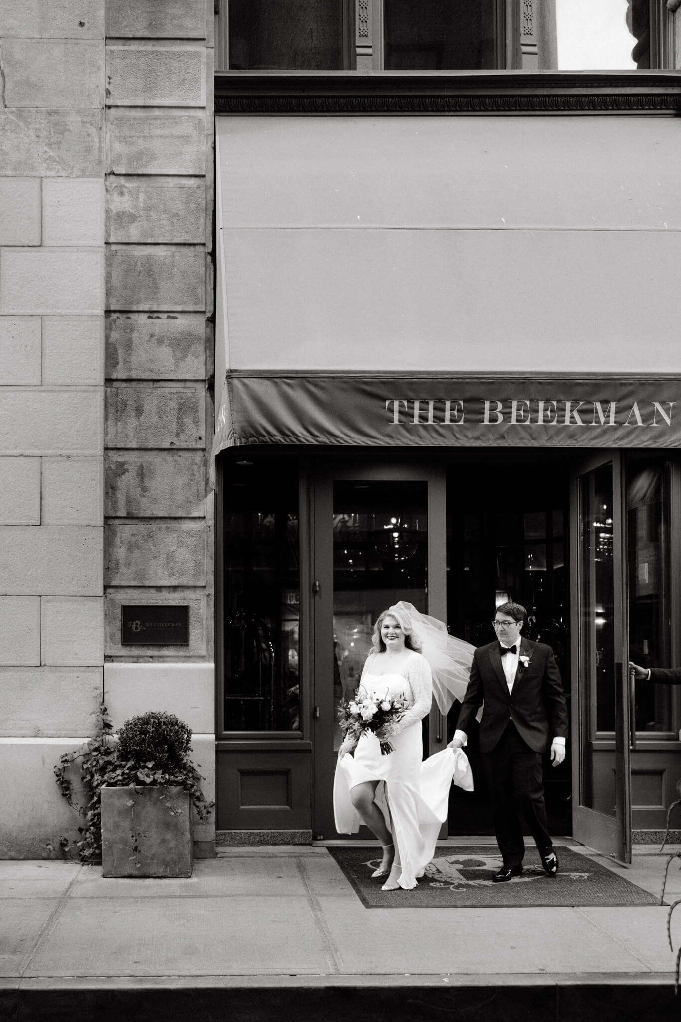 Black and white editorial photo of the bride and groom going out of the Beekman Hotel, NYC. Manhatta wedding image by Jenny Fu Studio