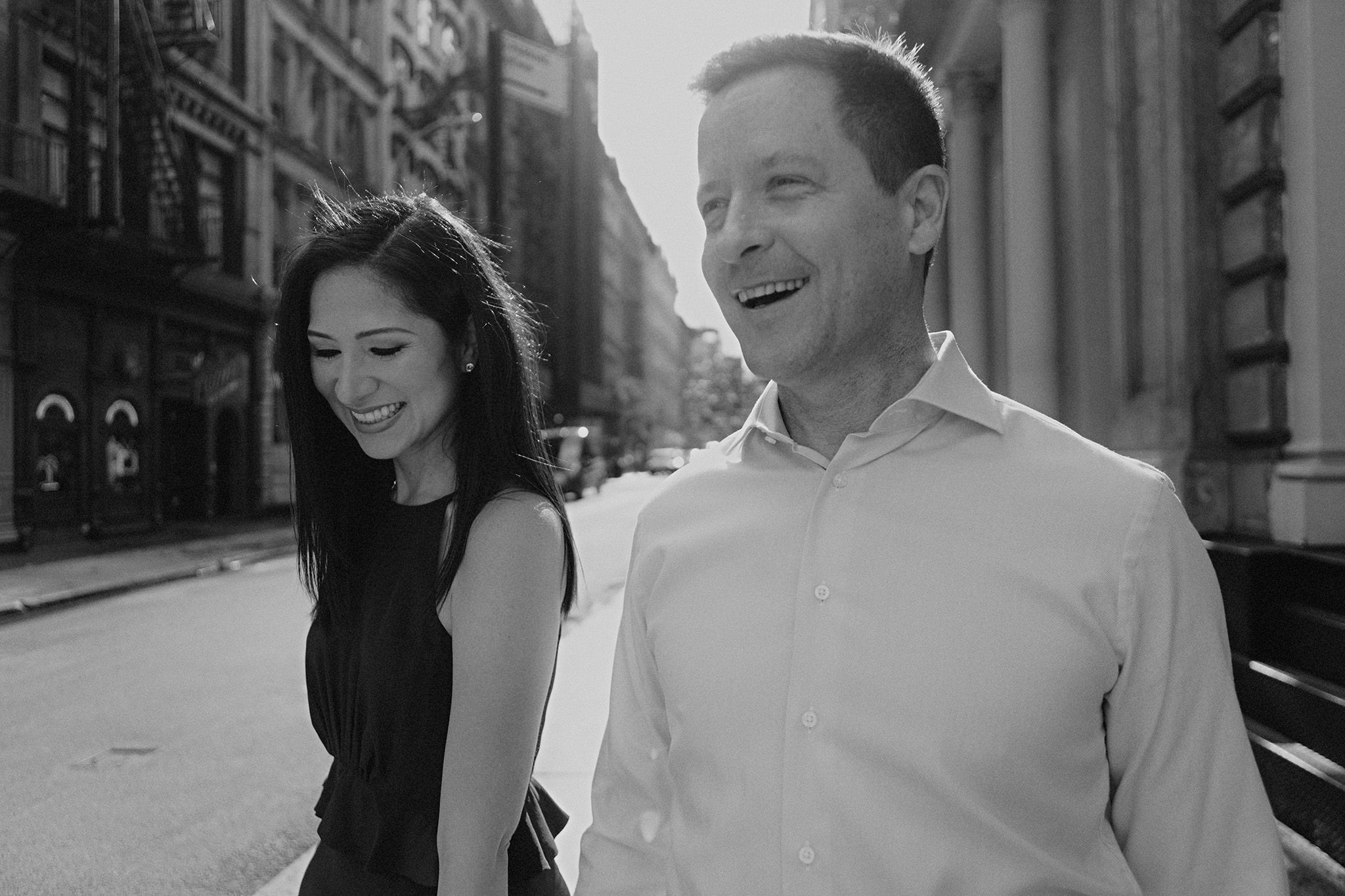 Black and white photo of a couple happily walking the streets of New York. Editorial NYC engagement photo by Jenny Fu Studio 