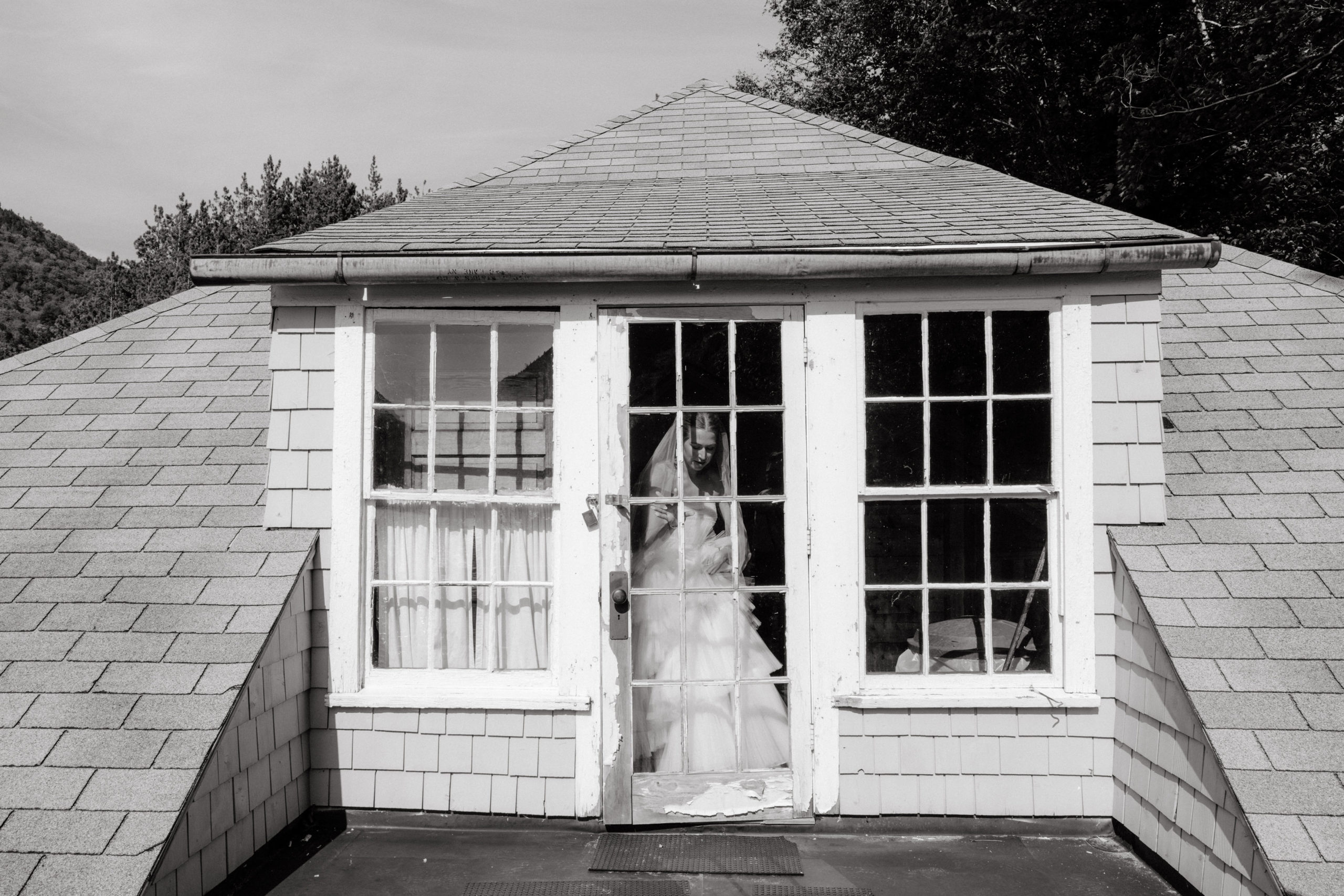 Black and white editorial photo of the bride inside an attic at The Ausable Club. New York elopement image by Jenny Fu Studio