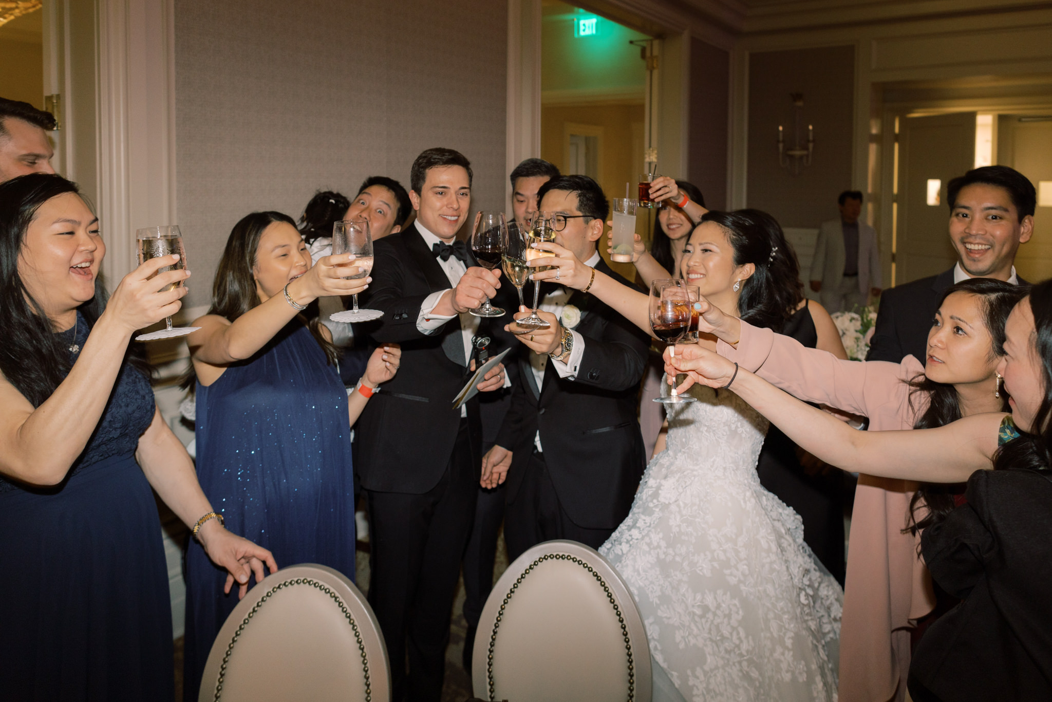 The bride, groom, and guests are lifting their wine glasses for a toast. NYC wedding image by Jenny Fu Studio