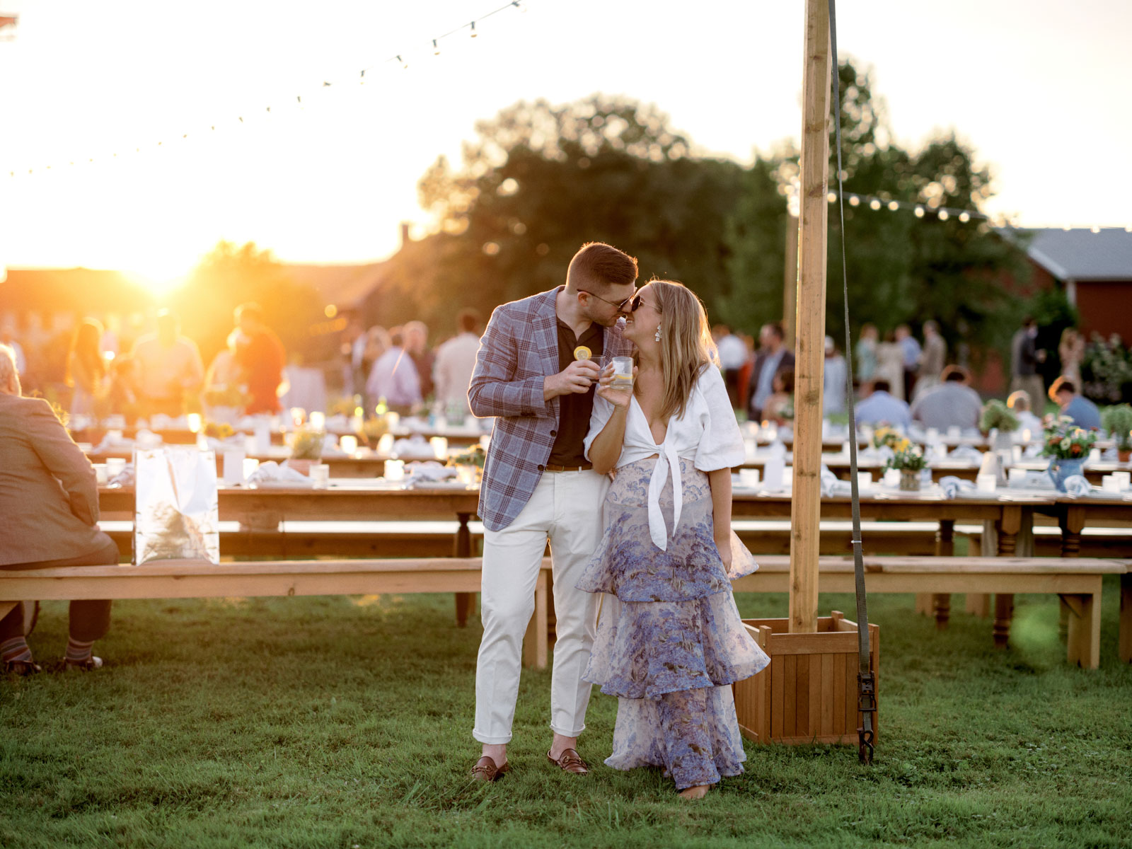 The couple is about to kiss each other. In the background are guests mingling with each other in the rehearsal dinner. Editorial image by Jenny Fu Studio