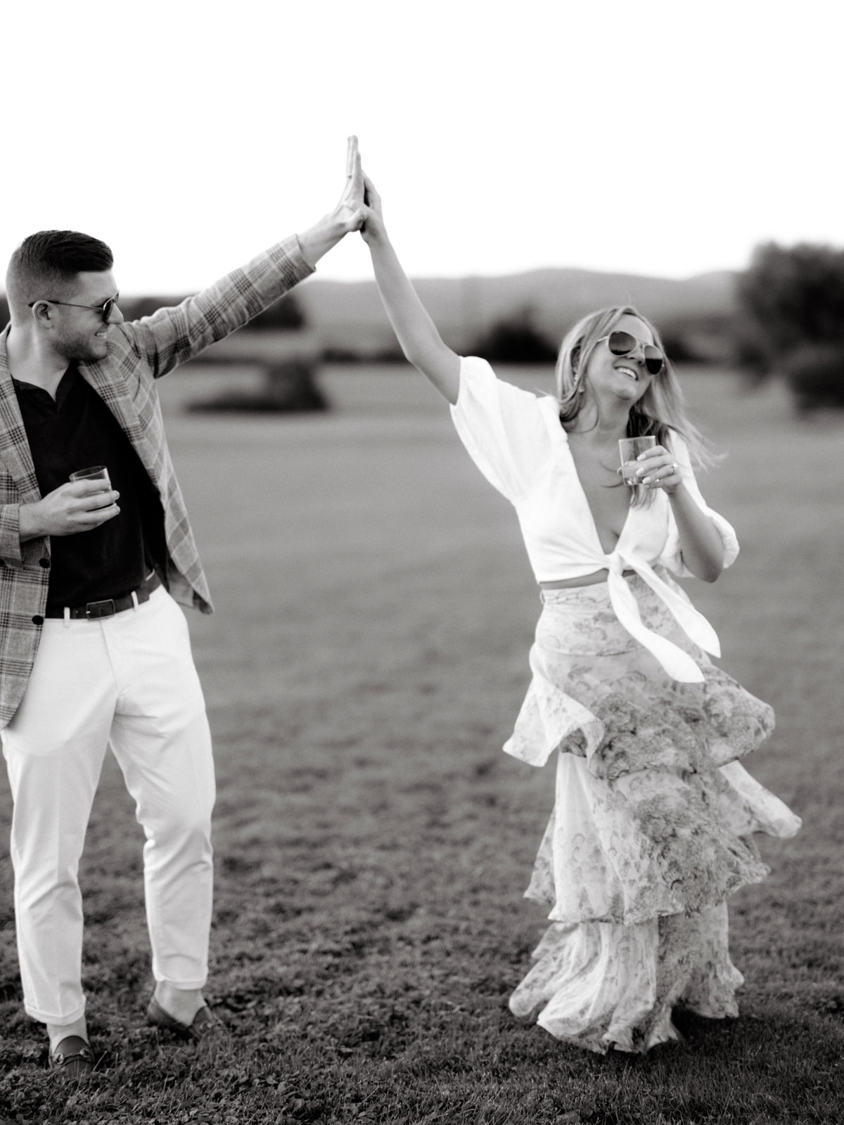 The bride and groom are happily dancing in an open field. Editorial rehearsal dinner image by Jenny Fu Studio.