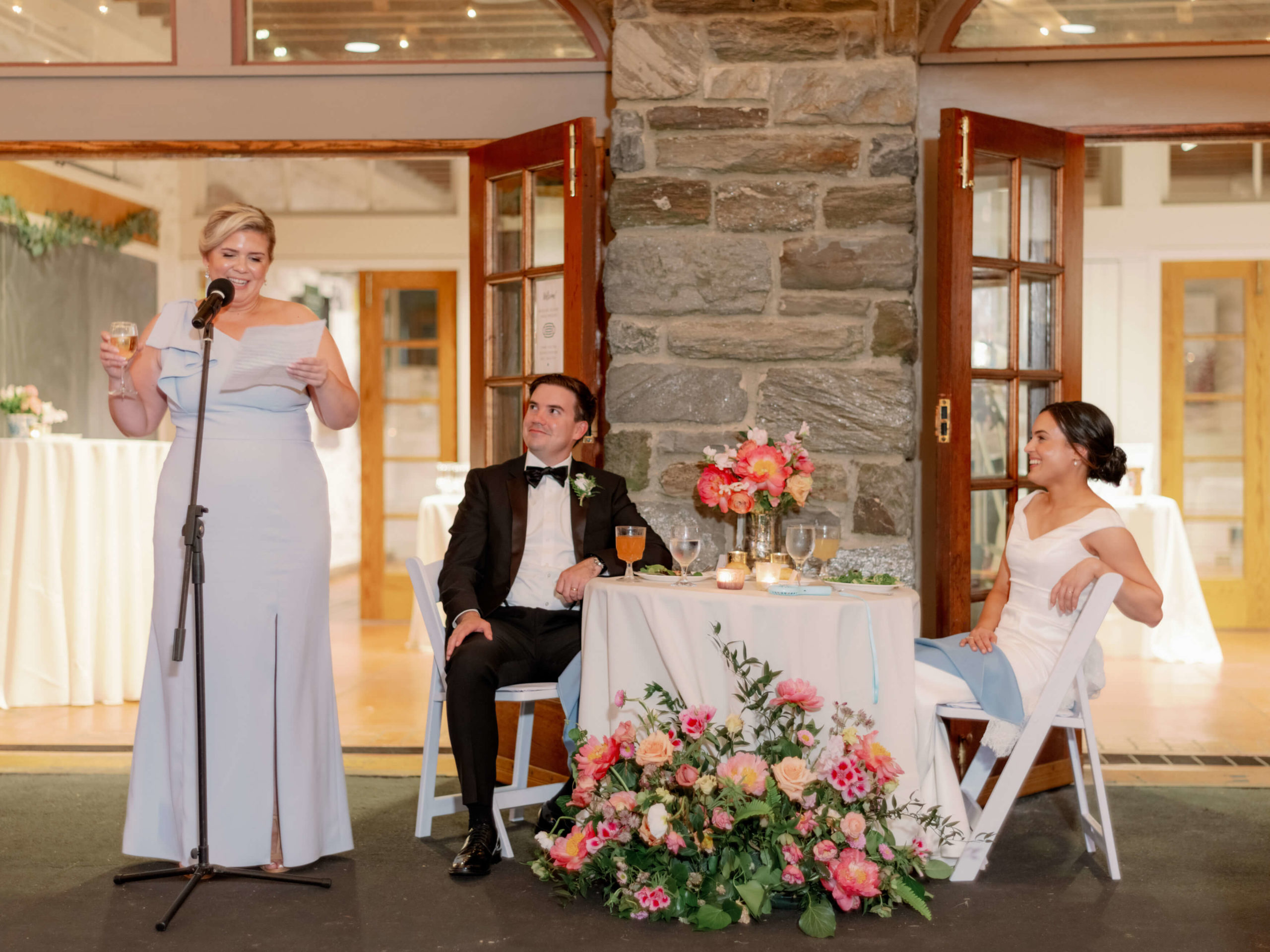 The bride and groom are happily watching a guest as she reads her speech. Image by Jenny Fu Studio