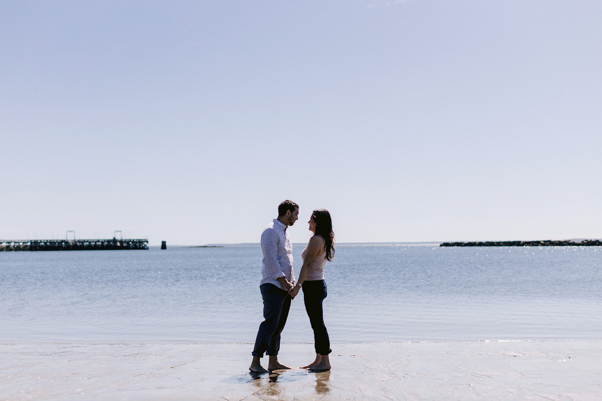 The engaged couple is romantically looking at each other on the beach in New York. Editorial image by Jenny Fu Studio