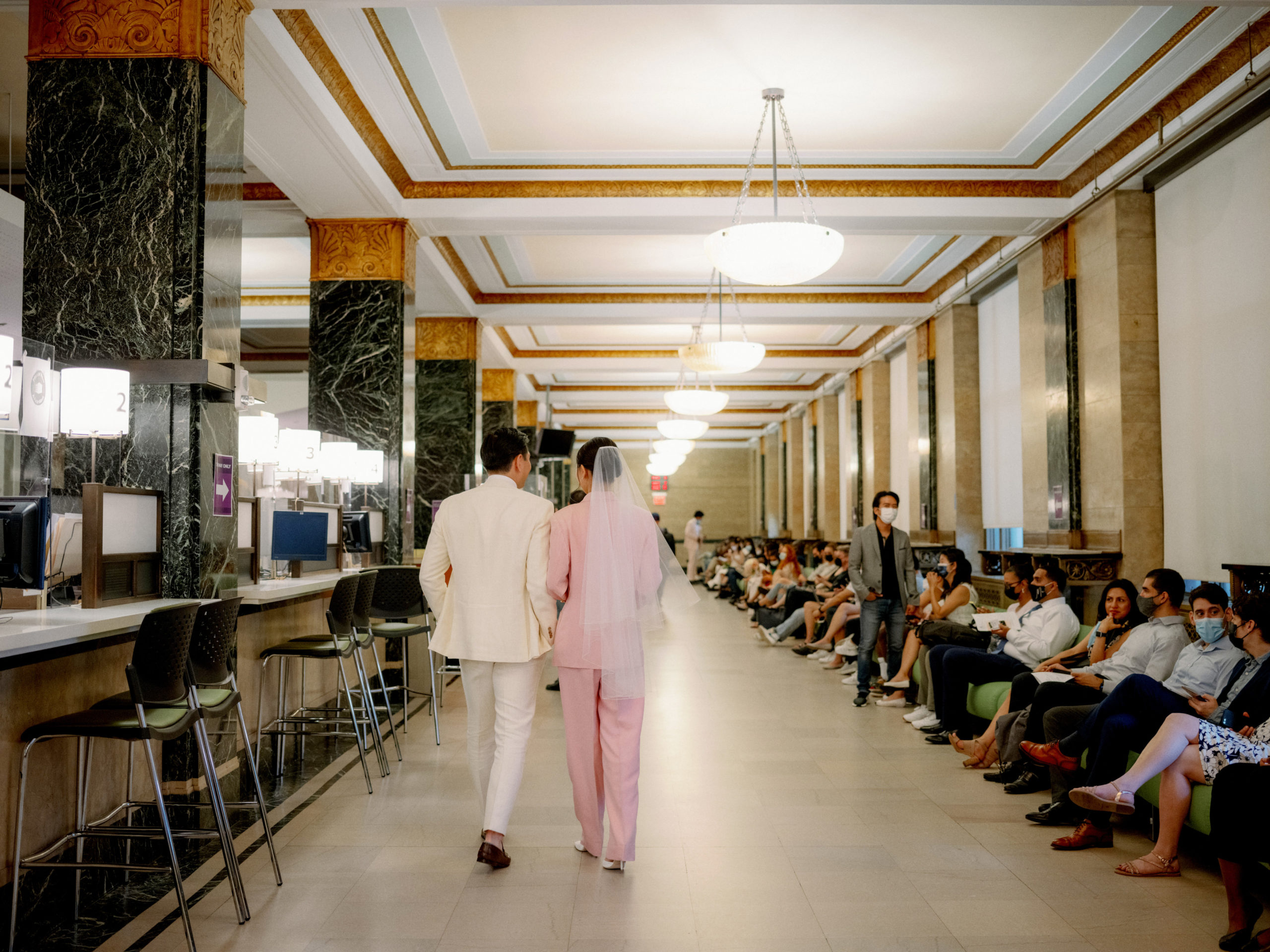 The bride and groom are walking in the hallway of NYC City Hall. Editorial Elopement Image  by Jenny Fu Studio
