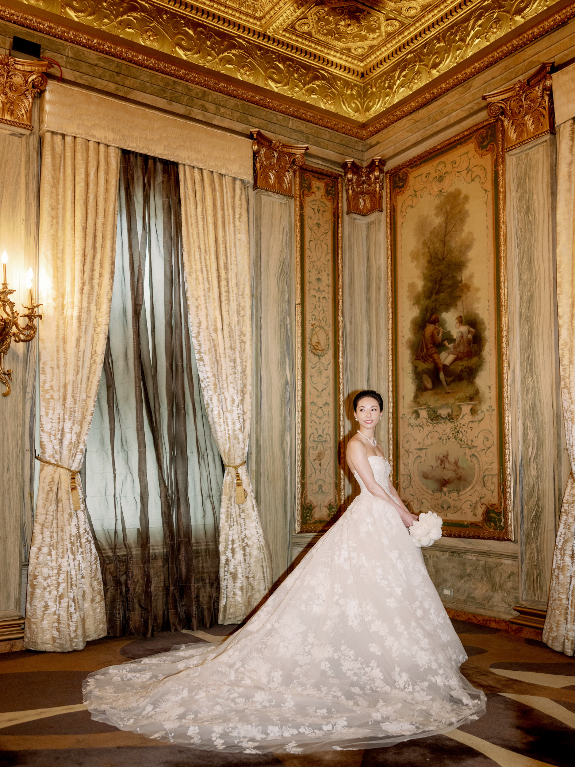The bride is standing, looking sideways, in her classic, beautiful wedding dress, with elegant hotel backdrop. Editorial photography by Jenny Fu Studio