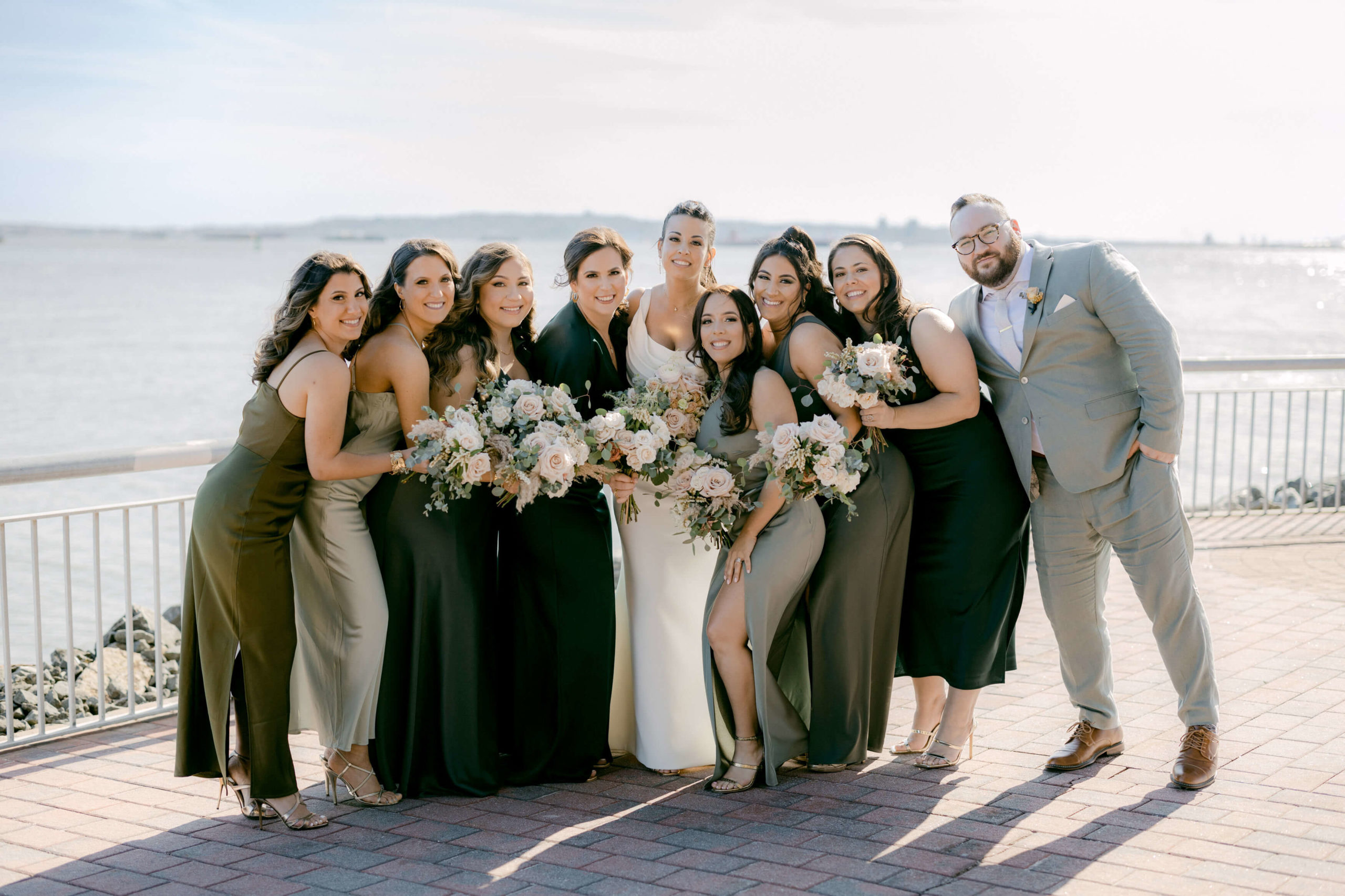 The bride and the bridesmaids are smiling while holding flower bouquets. Editorial wedding image by Jenny Fu Studio