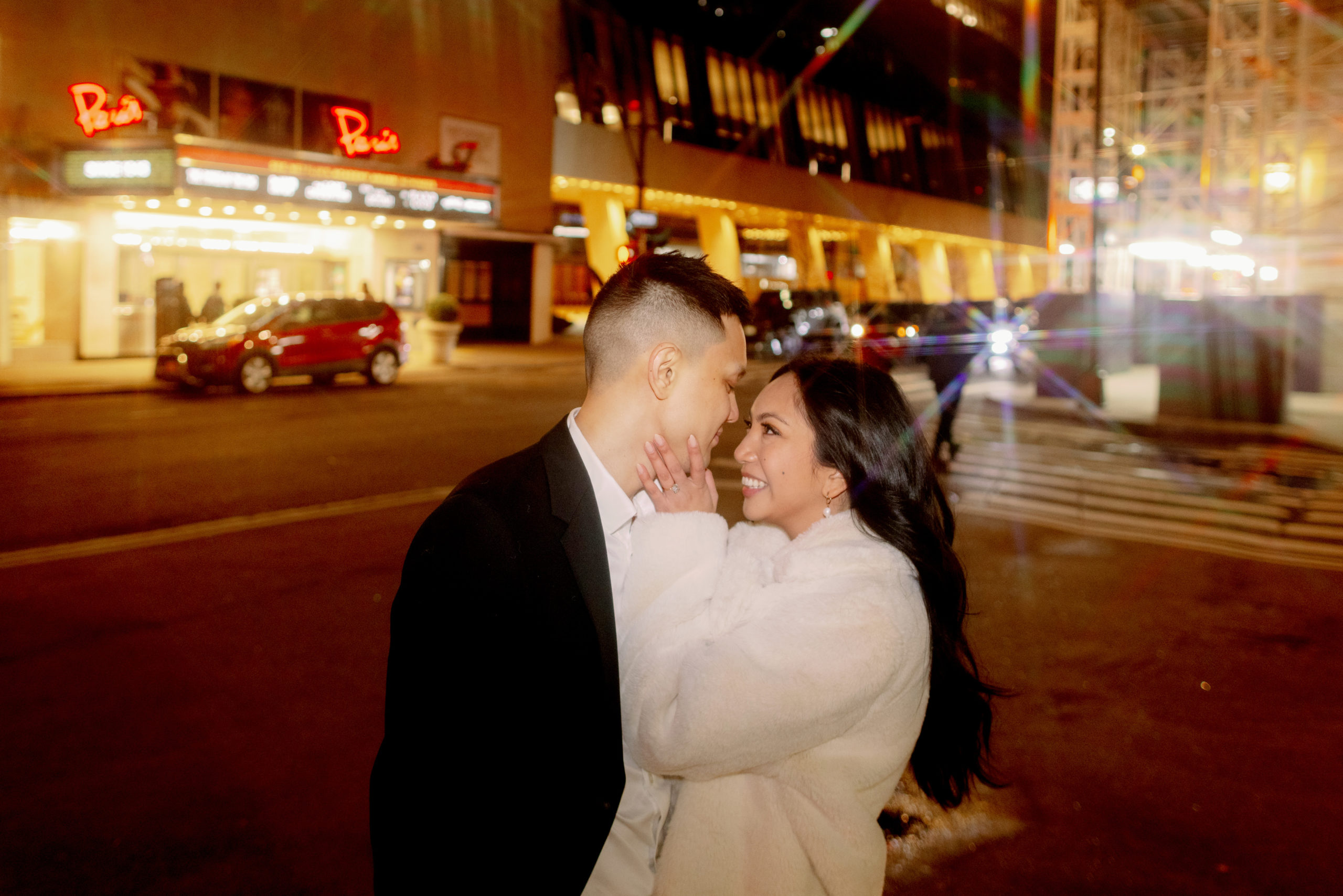 The engaged couple are happily staring at each other in the streets of New York at night. Photojournalistic Engagement image by Jenny Fu Studio