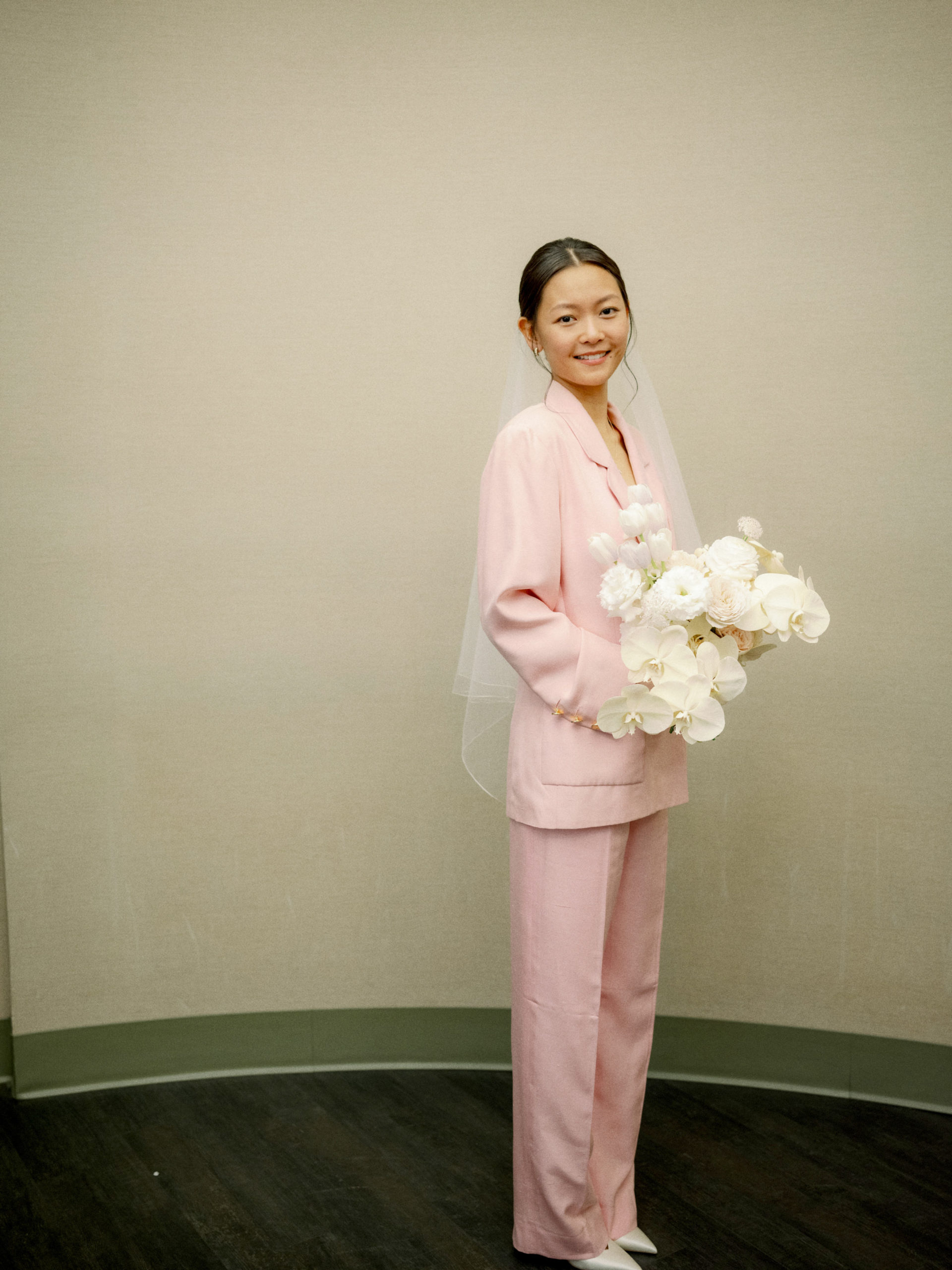 The pretty bride is wearing a baby pink wedding suit for her NYC city hall wedding. Editorial elopement Image by Jenny Fu Studio