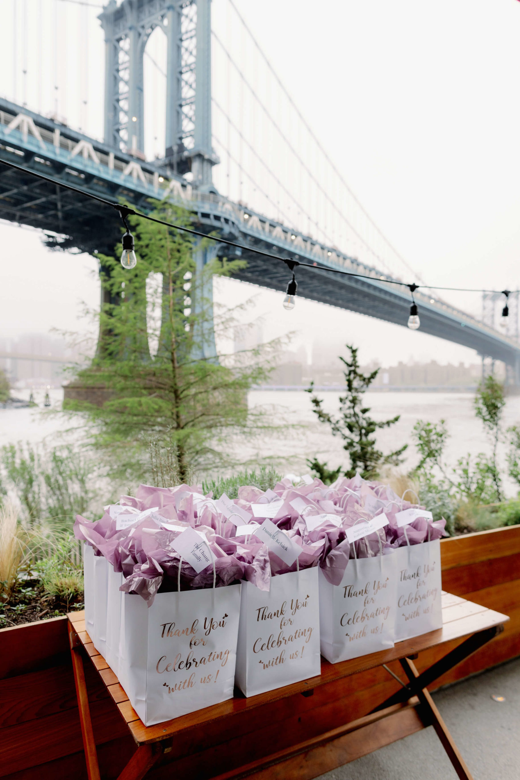 A bunch of paper bags filled with wedding favors on top of a wooden table at NYC. Hours of wedding photography image by Jenny Fu Studio