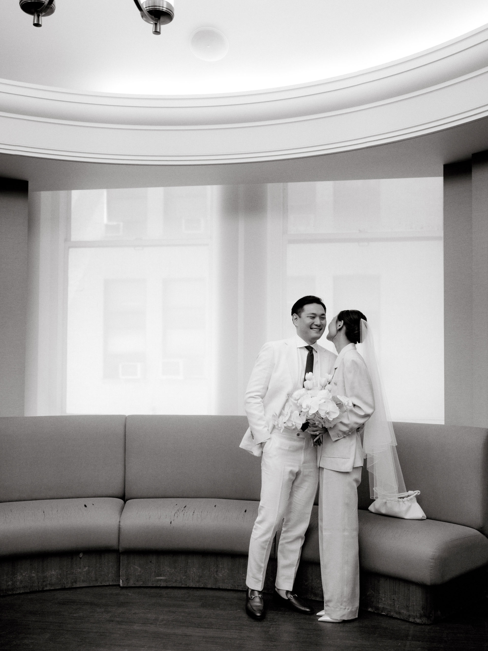 Black and white photo of the couple happily waiting for the wedding ceremony at NYC City Hall. Editorial image by Jenny Fu Studio