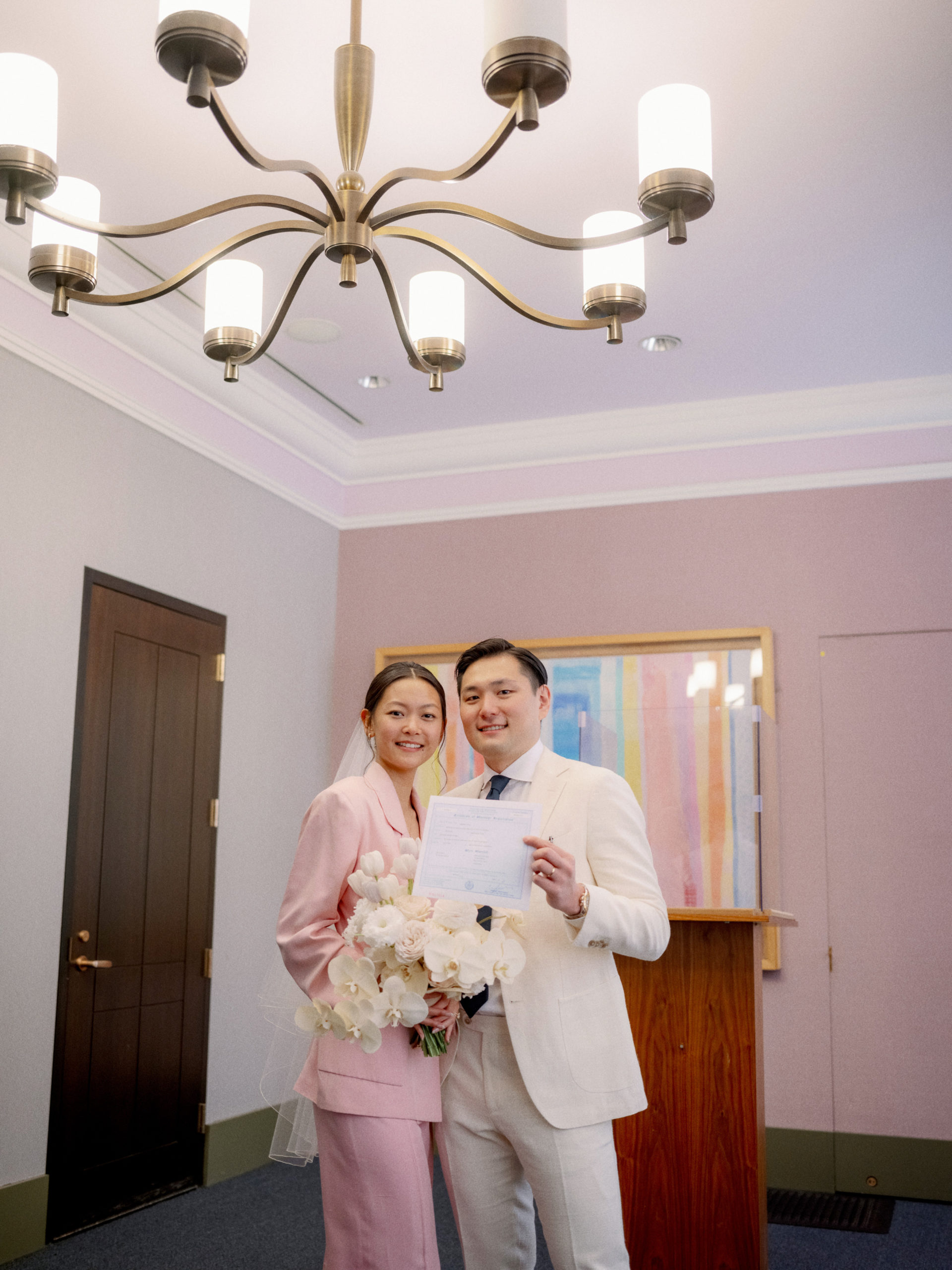 The newly-weds are holding their marriage certificate. Image by Jenny Fu Studio
