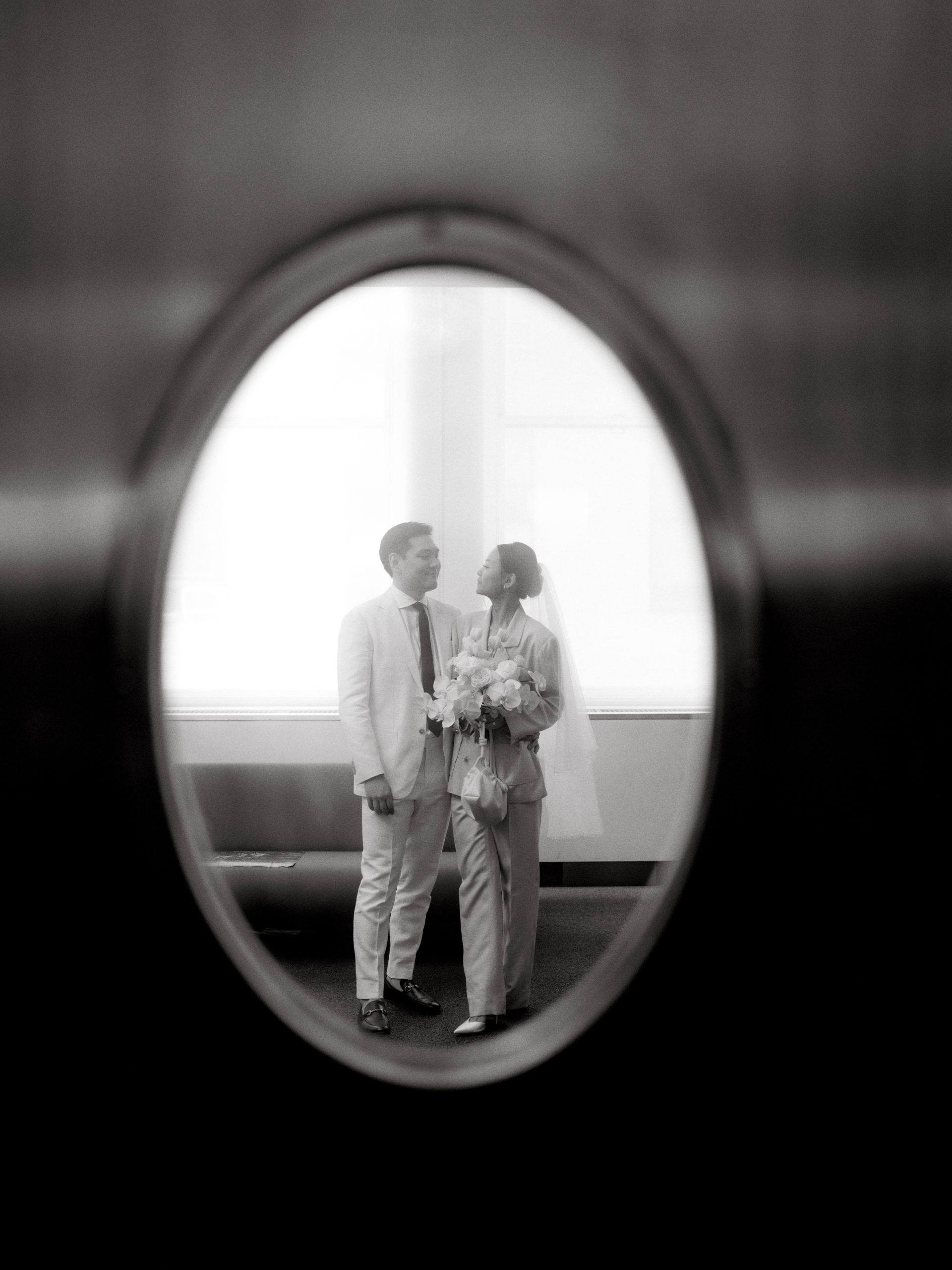 Black and white photo of the newlyweds looking at each other at NYC City Hall. Editorial image by Jenny Fu Studio