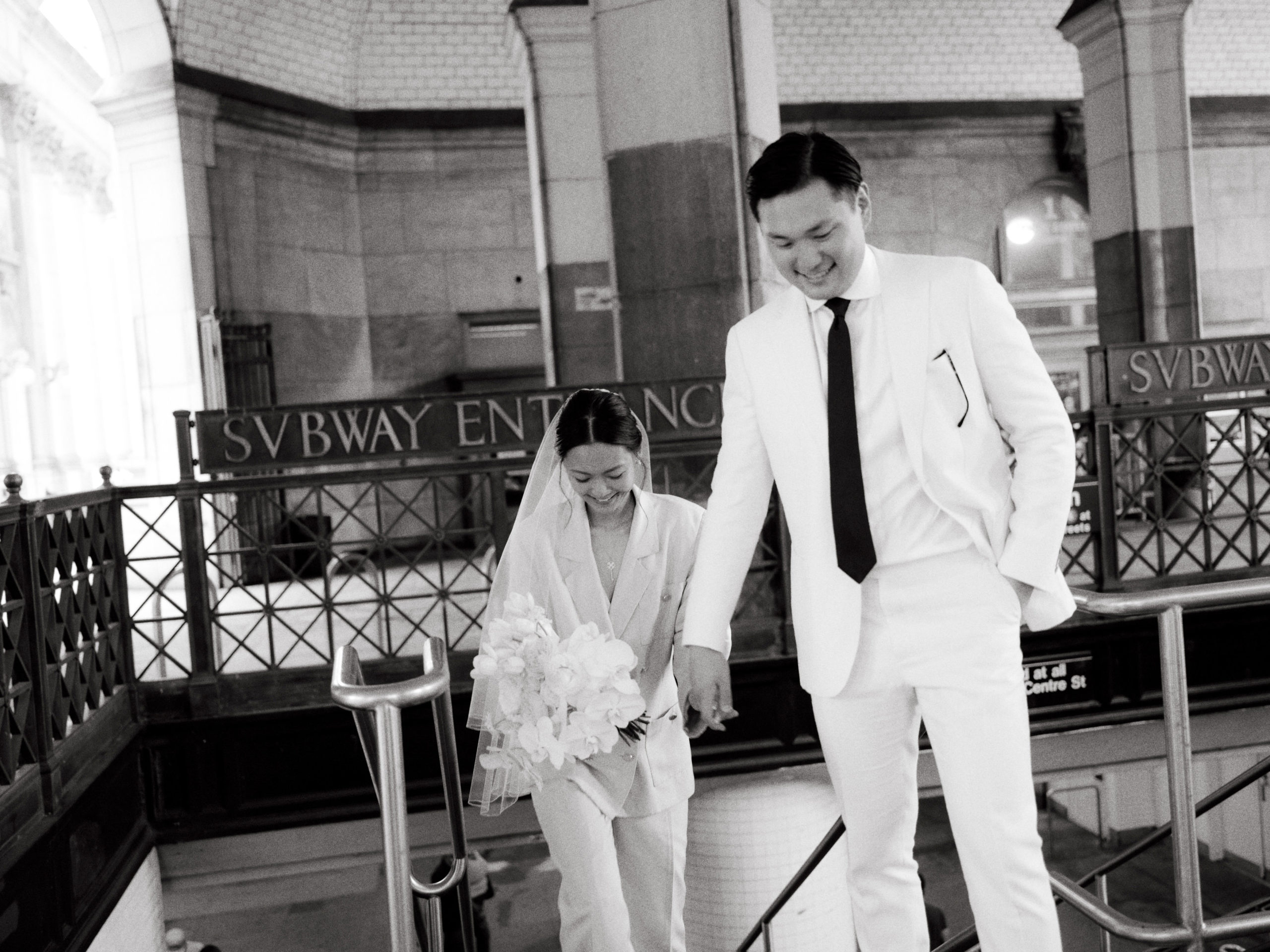 The newlyweds are walking in the subway terminal. Personalized NYC City Hall wedding image by Jenny Fu Studio