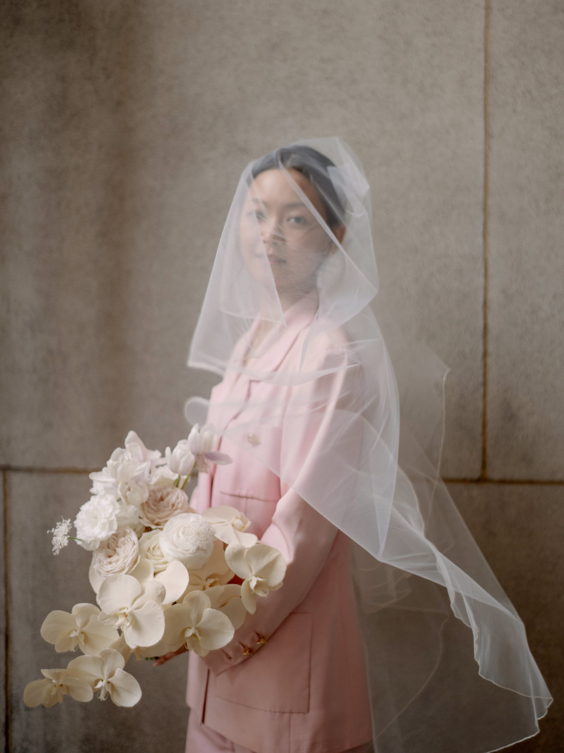 Editorial image of the bride wearing her veil and holding her flower bouquet. Personalized NYC City Hall wedding image by Jenny Fu Studio