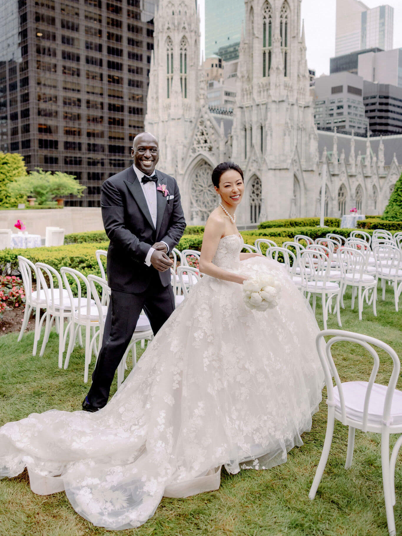 The bride and groom are smiling happily at 620 Loft and Garden with St. Patrick's Cathedral in the Background. Image by Jenny Fu Studio