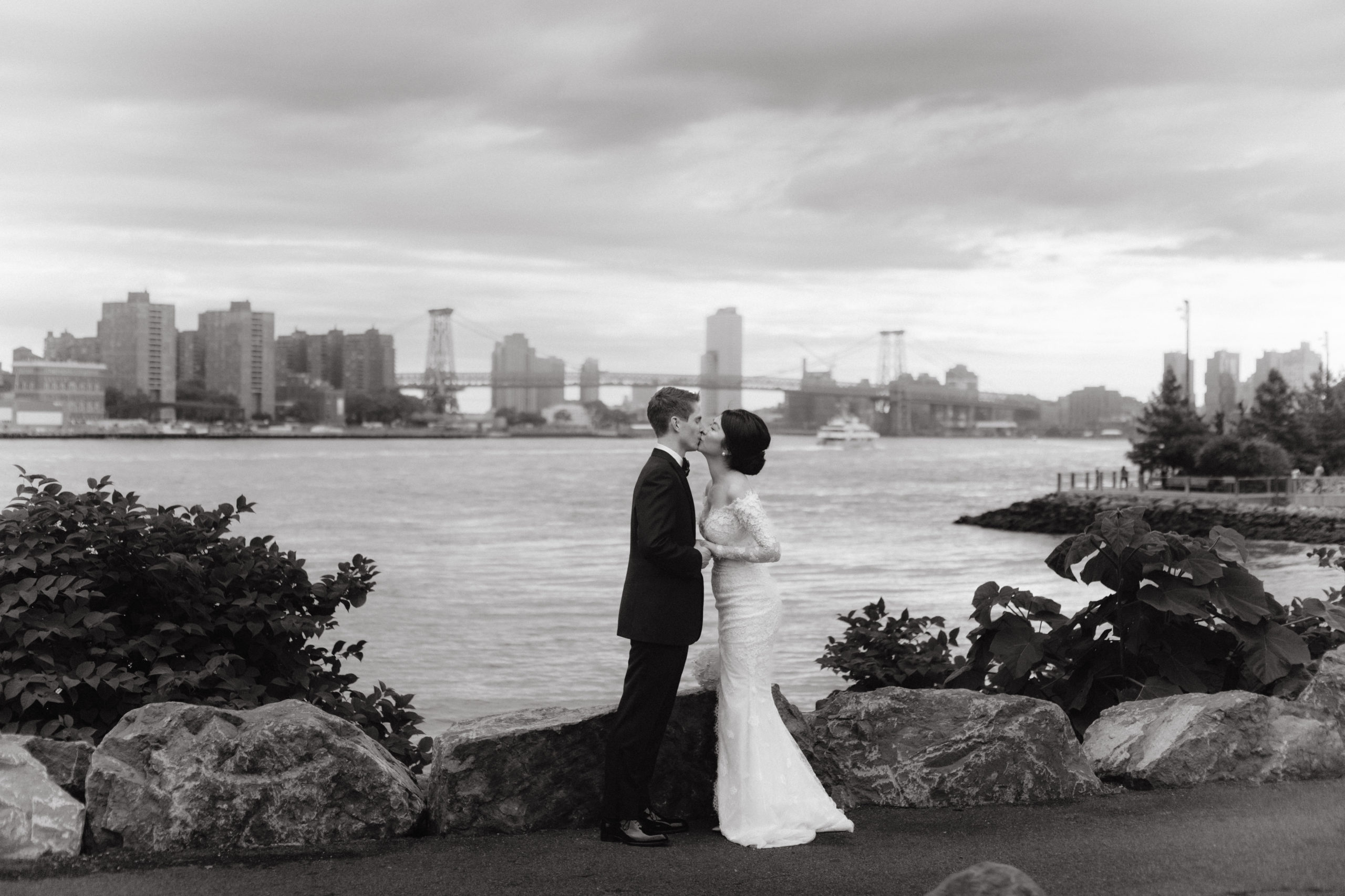 Black and white image of the couple kissing at Brooklyn Bridge Park. NYC City Hall wedding photos image by Jenny Fu Studio