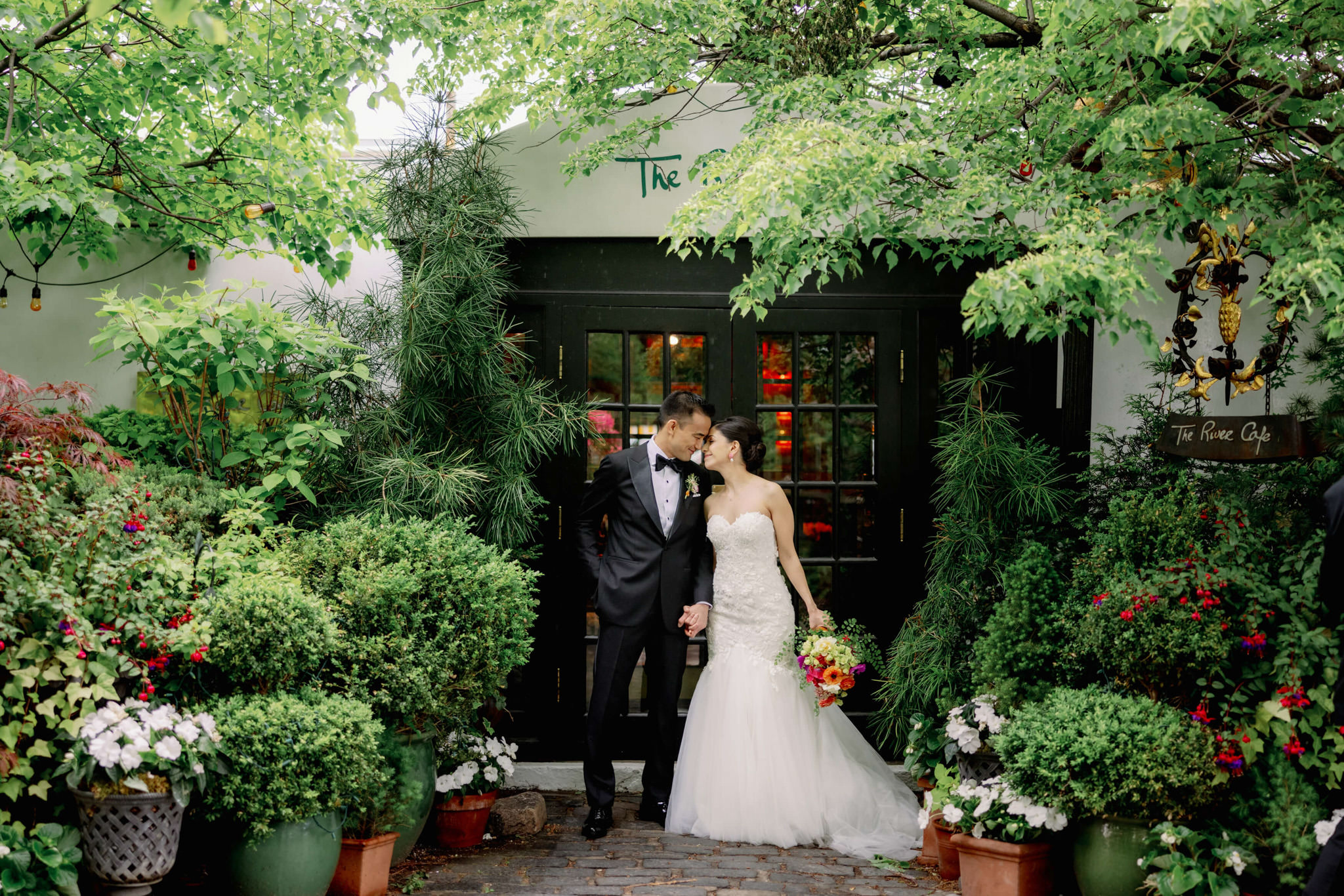 The bride and groom are staring at each other close in front of The River Cafe entrance. Editorial wedding image by Jenny Fu Studio