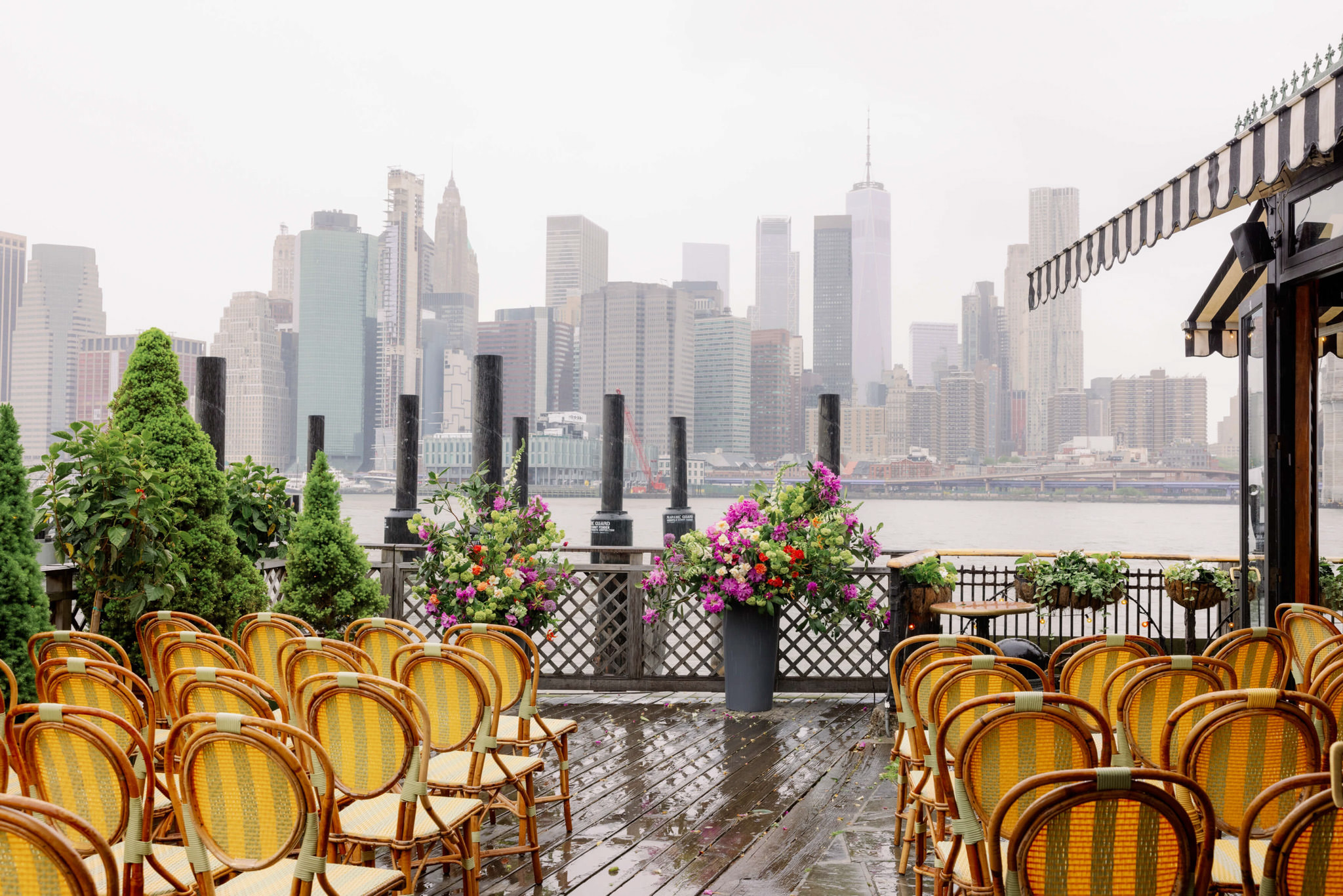 The wedding ceremony area at The River Cafe has wet floors because of the rain. Editorial wedding image by Jenny Fu Studio