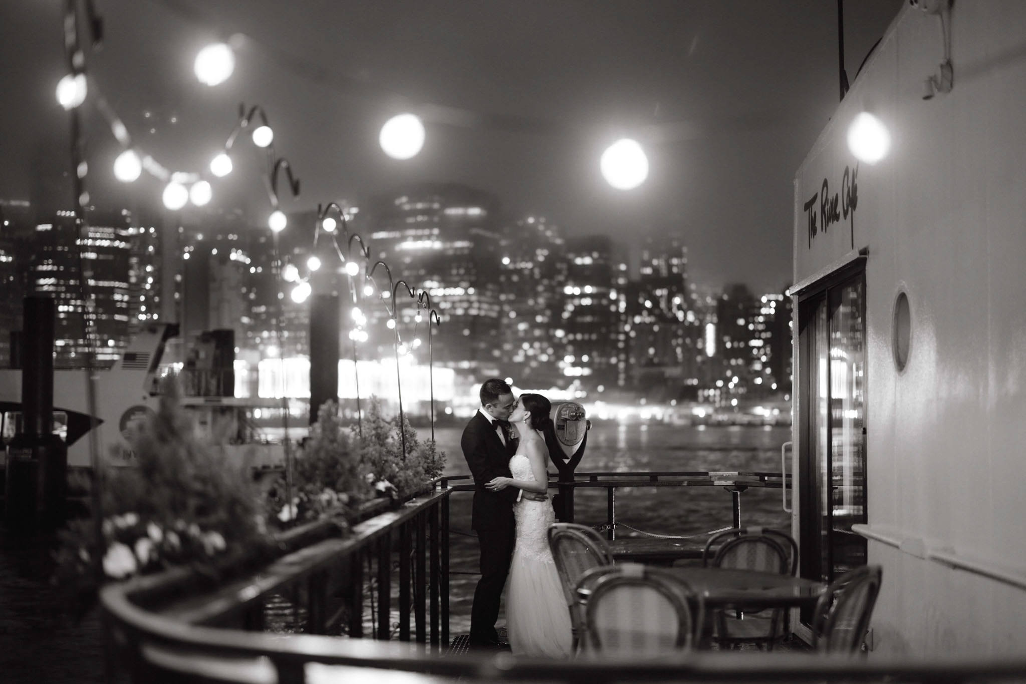 Black and white photo of the newly-wed kissing by the river at The River Cafe. Image by Jenny Fu Studio