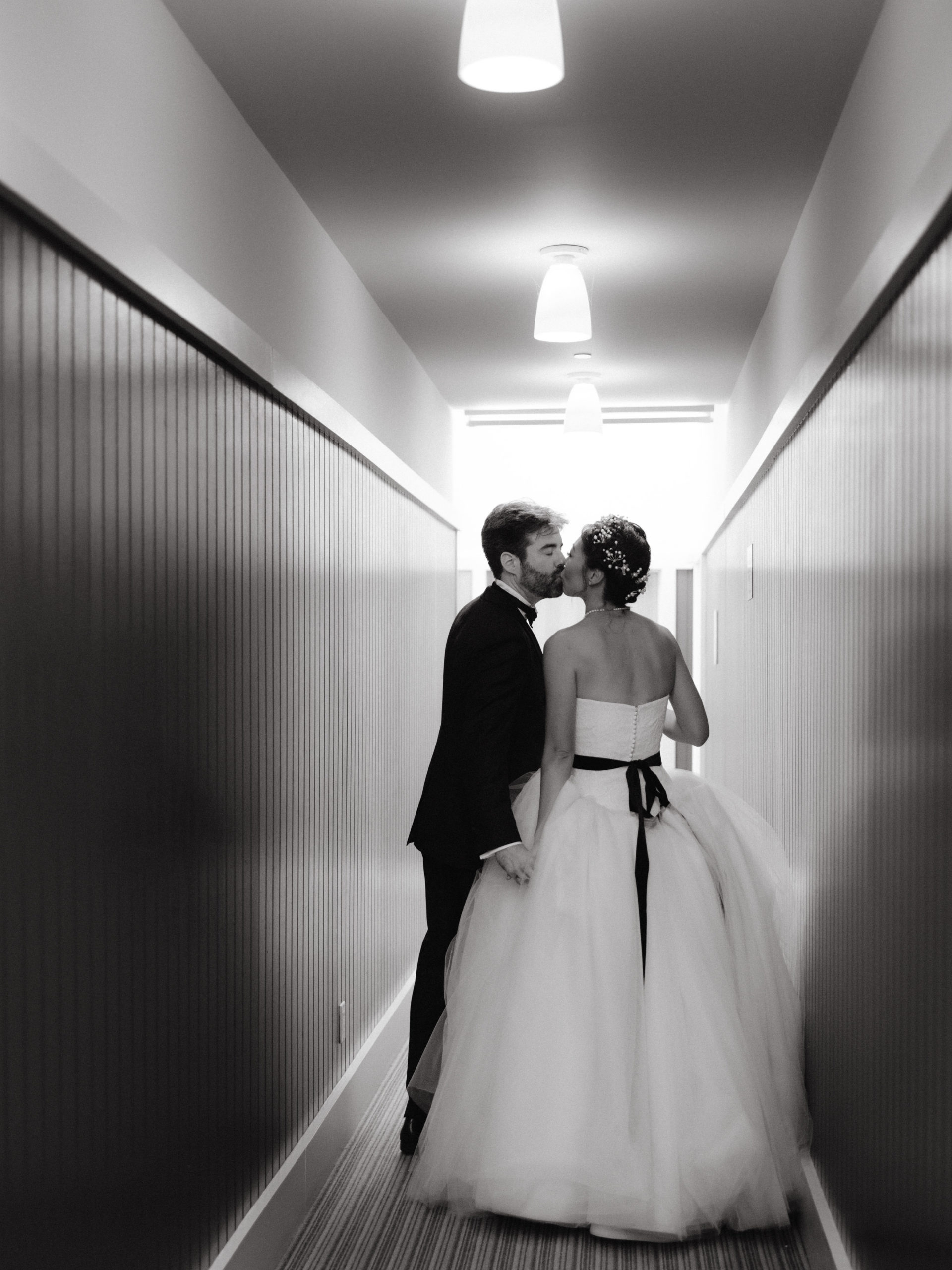 A black and white photo of the bride and groom kissing on a hallway. Destination wedding rules image by Jenny Fu Studio