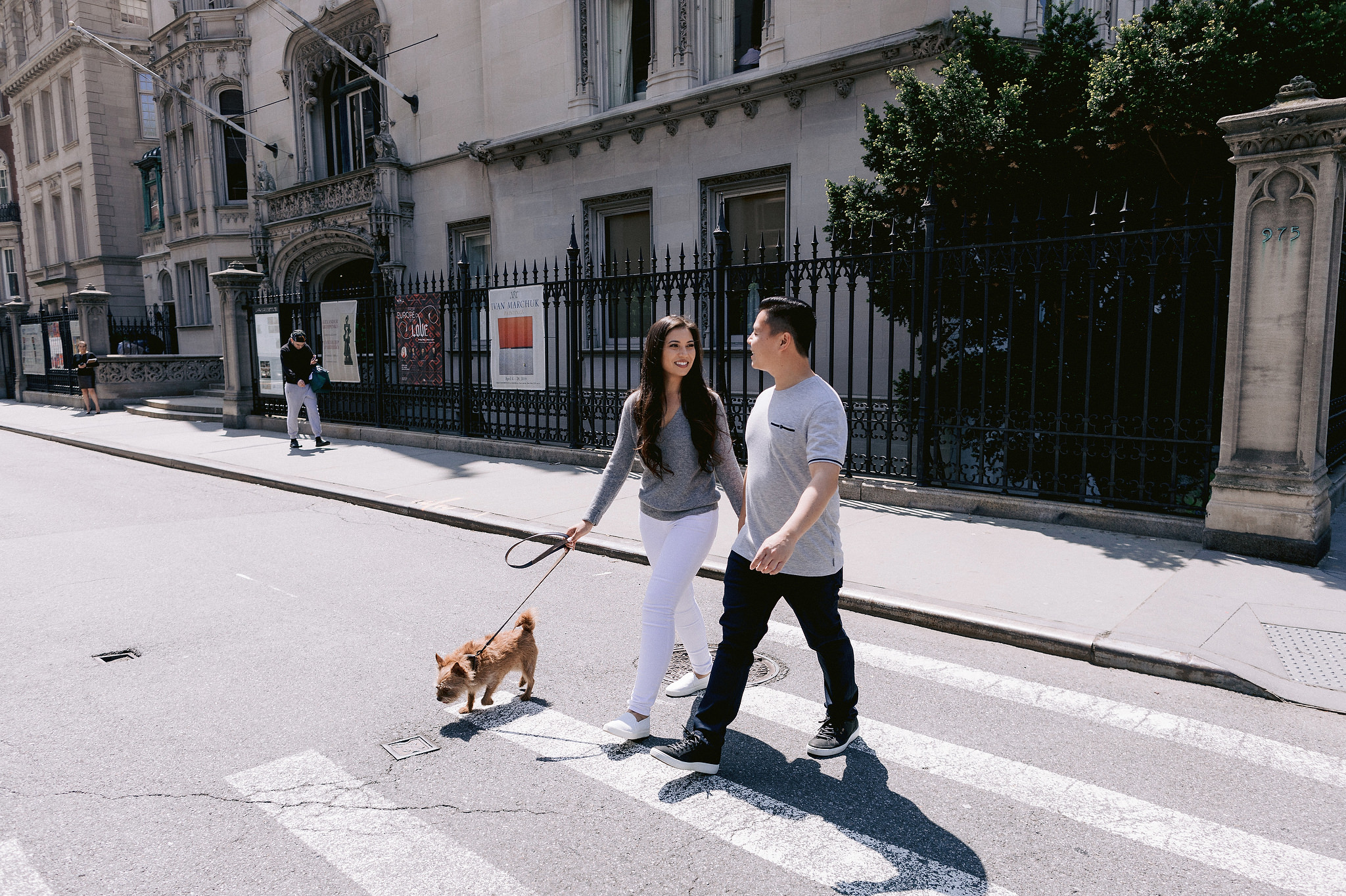 The engaged couple is crossing the street in NYC with their dog. Engagement session with pets photo by Jenny Fu Studio.