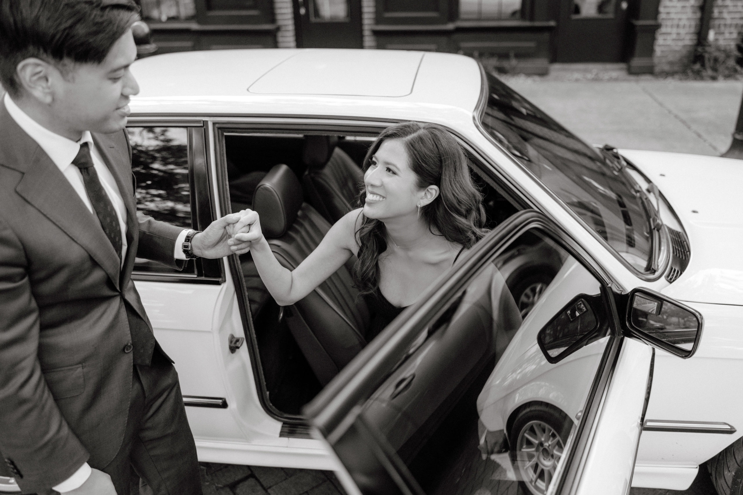 Black and white image of the man escorting his fiancée as she goes out of the car. Engagement photos by Jenny Fu Studio