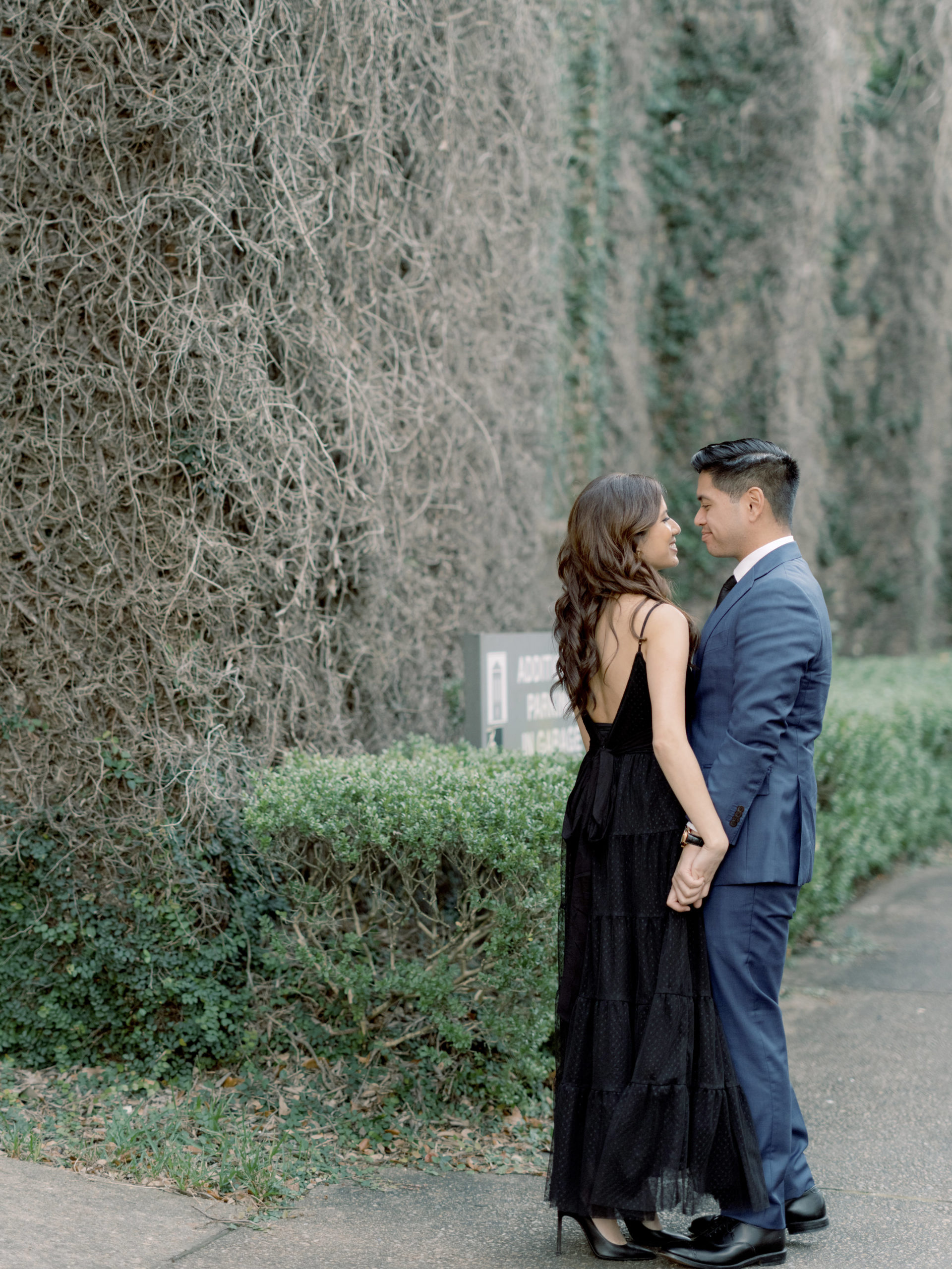 The engaged couple are standing close to each other in front of an ivy-covered building. Editorial Engagement photos by Jenny Fu Studio