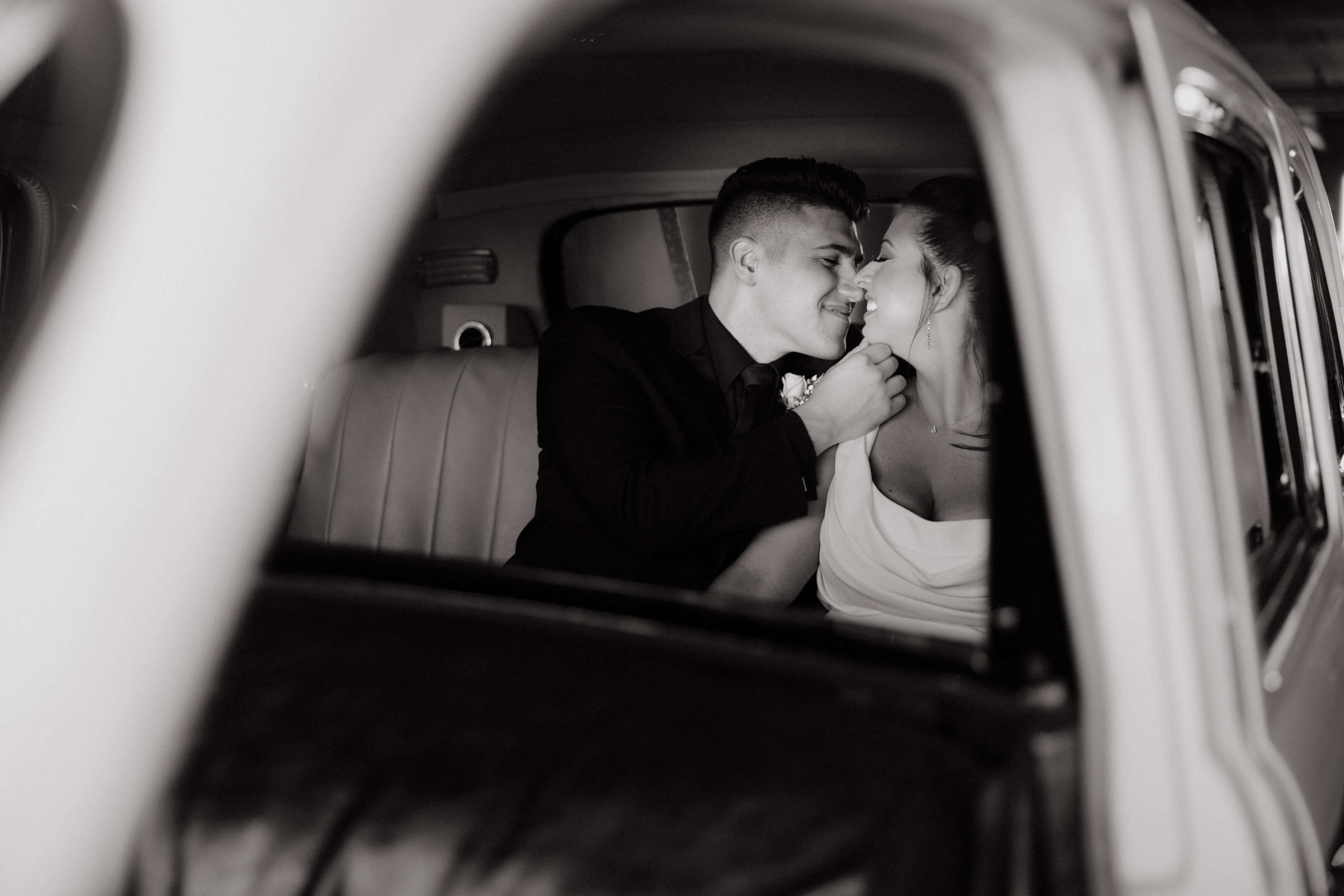 Black and white photo of the romantic bride and groom inside a car. Image by Jenny Fu Studio 