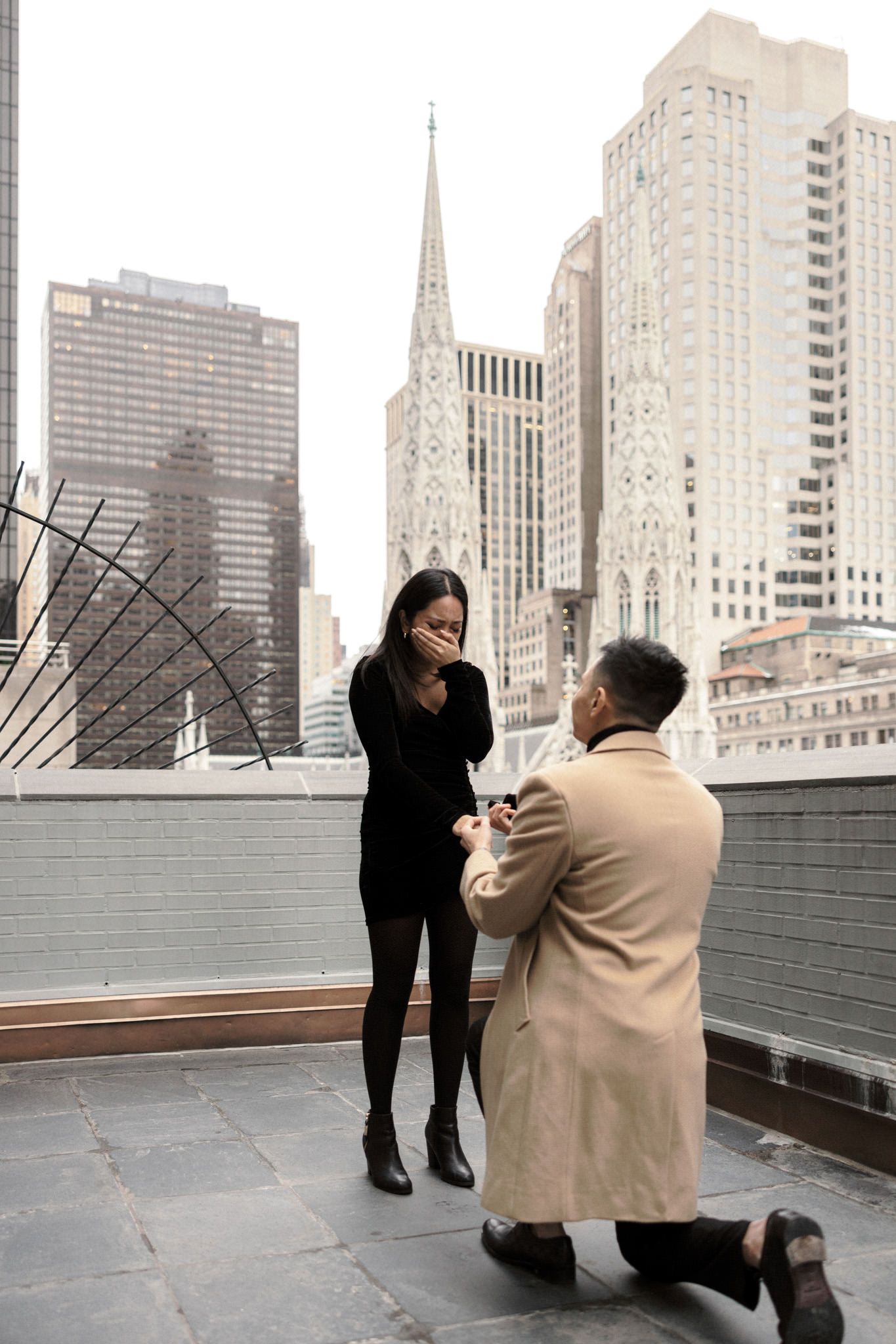 The man is down on one knee, showing his future fiancée the ring while the woman is emotional. Proposal in NYC image by Jenny Fu Studio