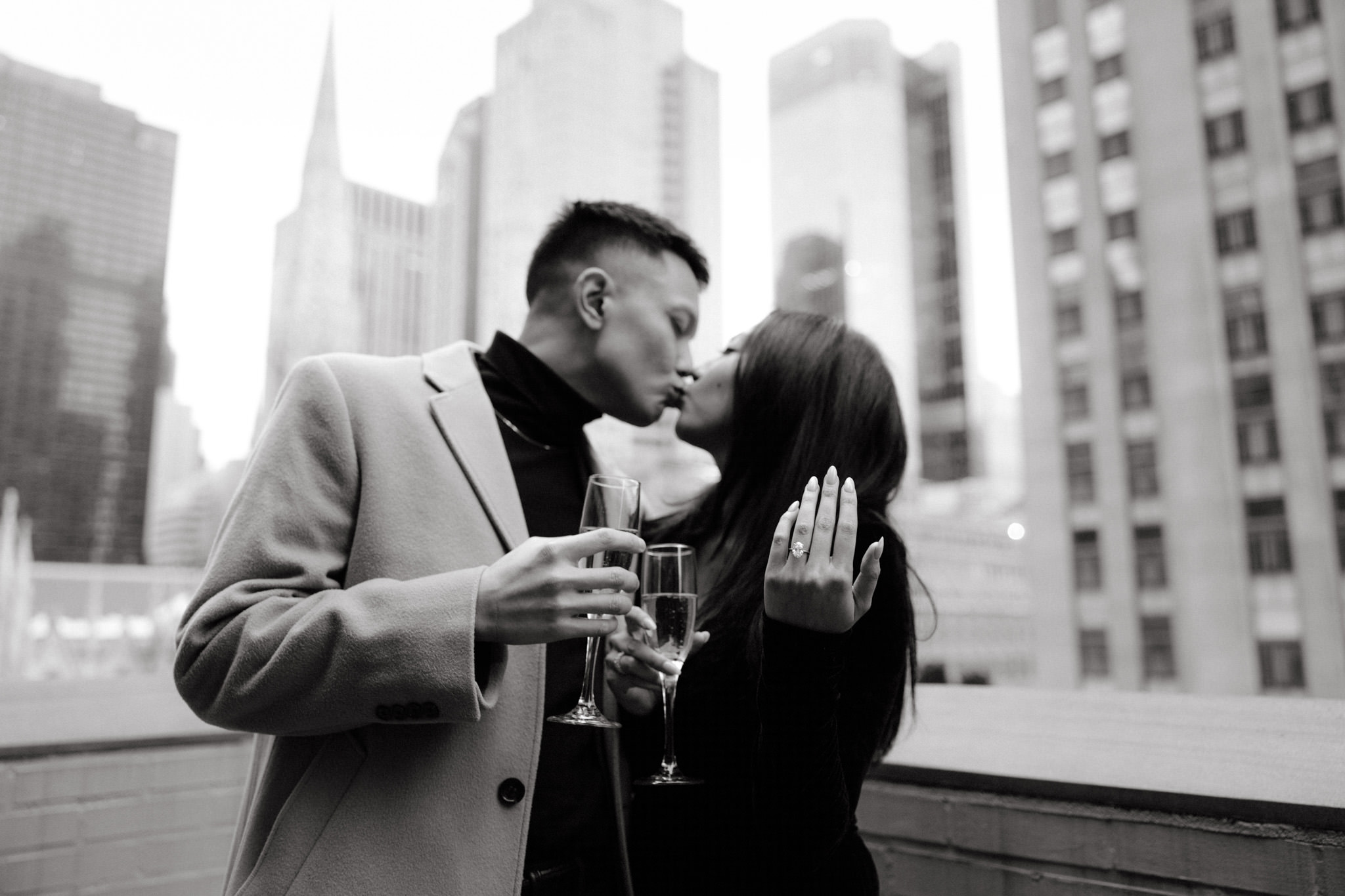 Black and white photo of the couple kissing after the proposal, the woman showing her engagement ring. Image by Jenny Fu Studio