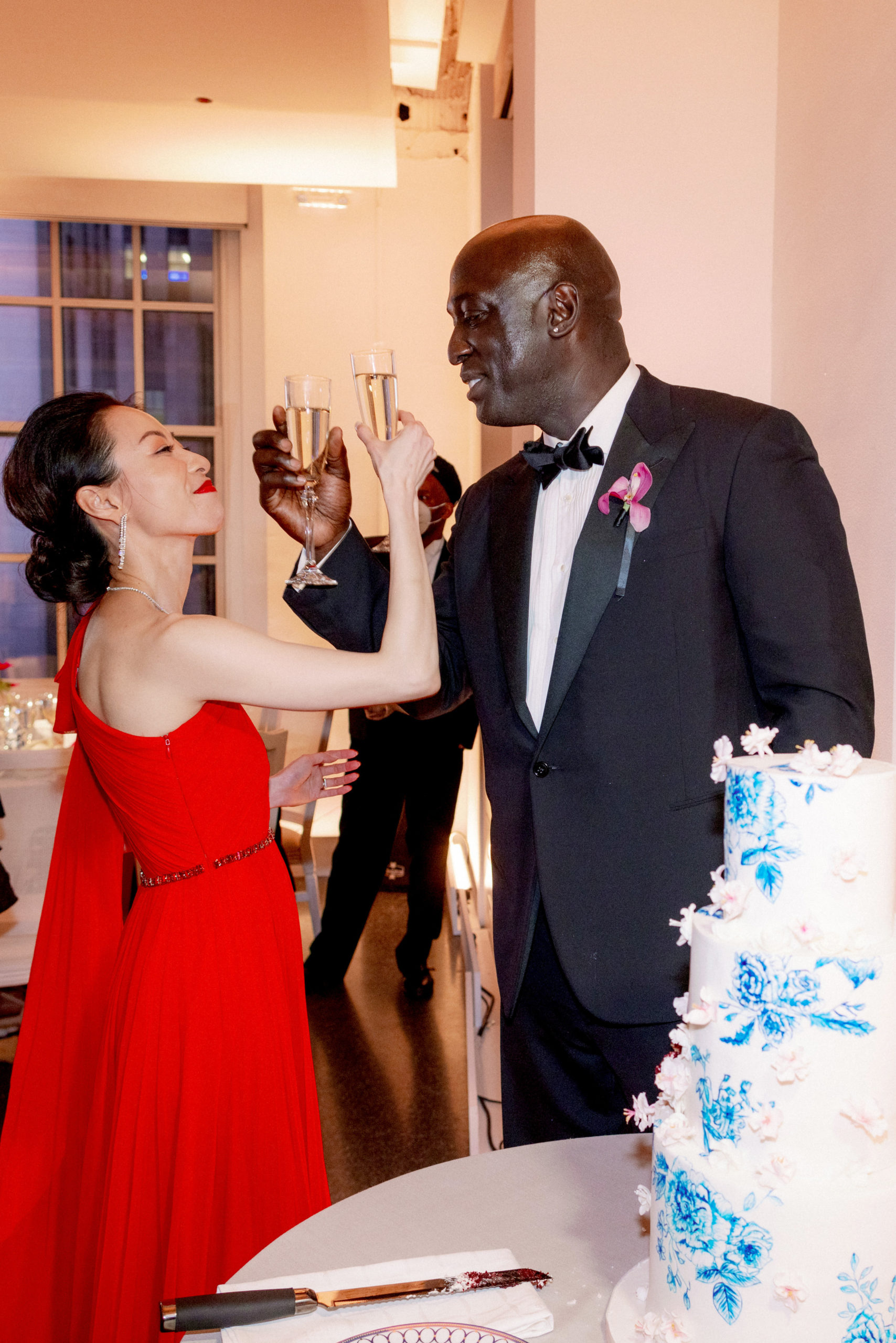 The newly-weds are doing a toast beside their wedding cake. Luxury wedding cake image by Jenny Fu Studio NYC