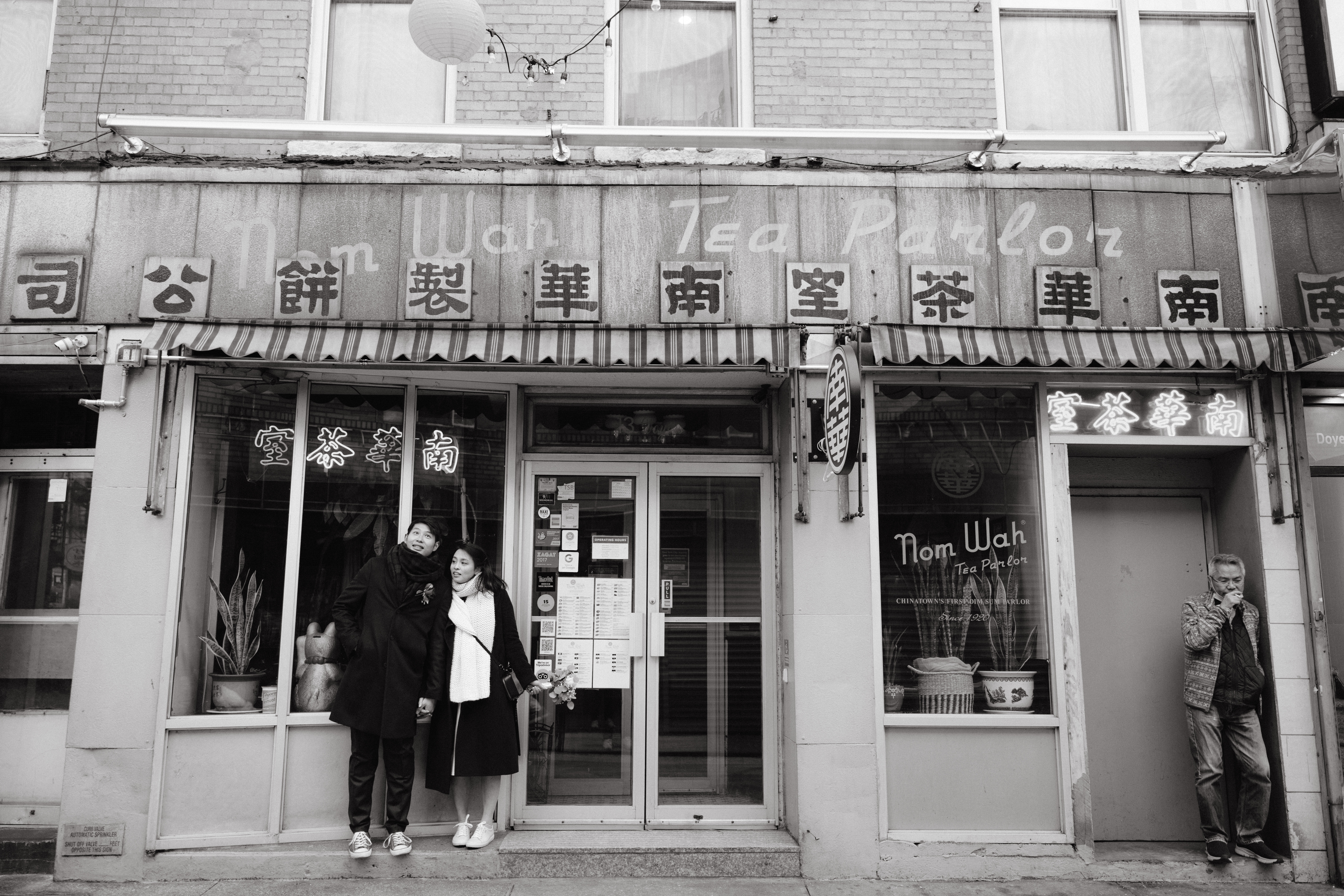 Black and white image of the newly-weds in front of a tea parlor in NYC Chinatown. Image by Jenny Fu Studio