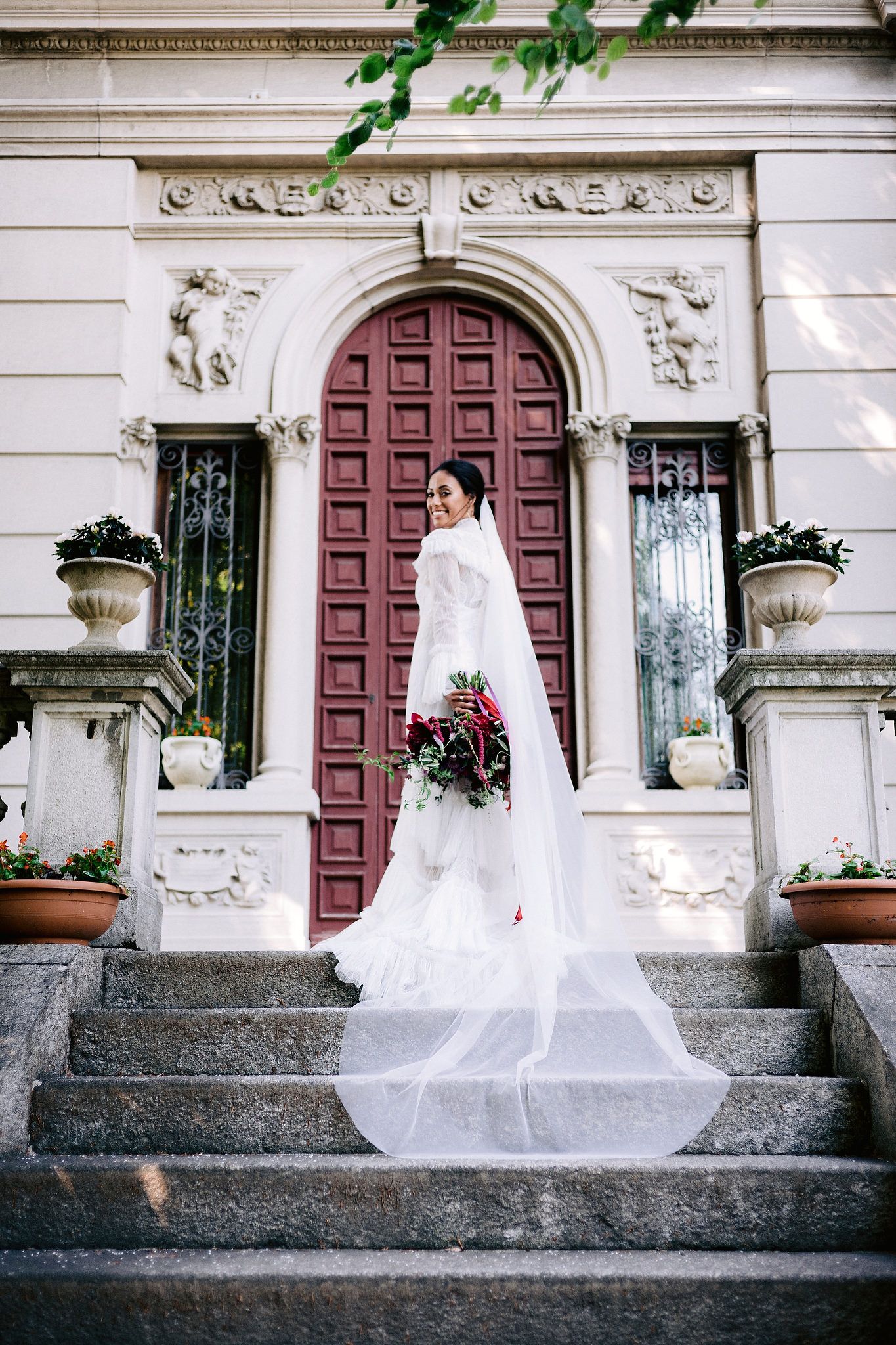 The bride is standing on the top of the stairs, her long veil flowing down at Villa Confalonieri, Lake Como