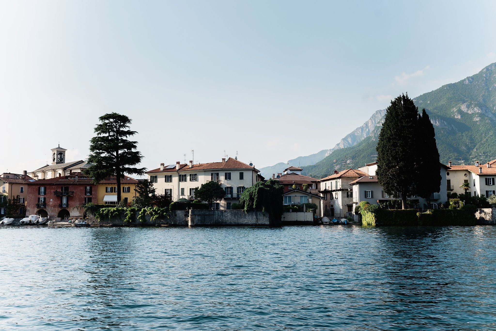 Lake Como with houses and trees in the background. Wedding in Italy image by Jenny Fu Studio