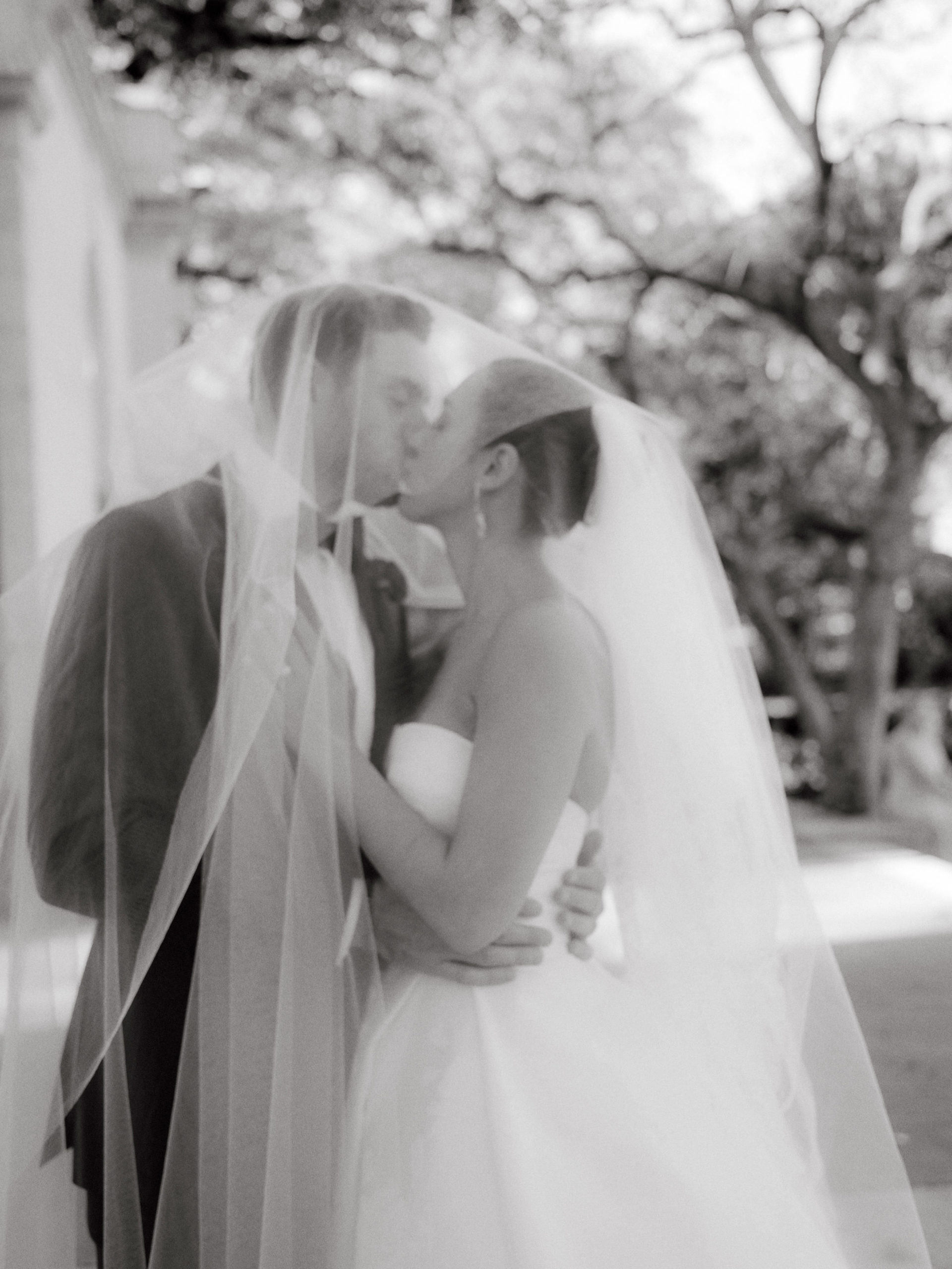Black and white film wedding photograph of the bride and groom kissing. Luxury wedding venues image by Jenny Fu Studio